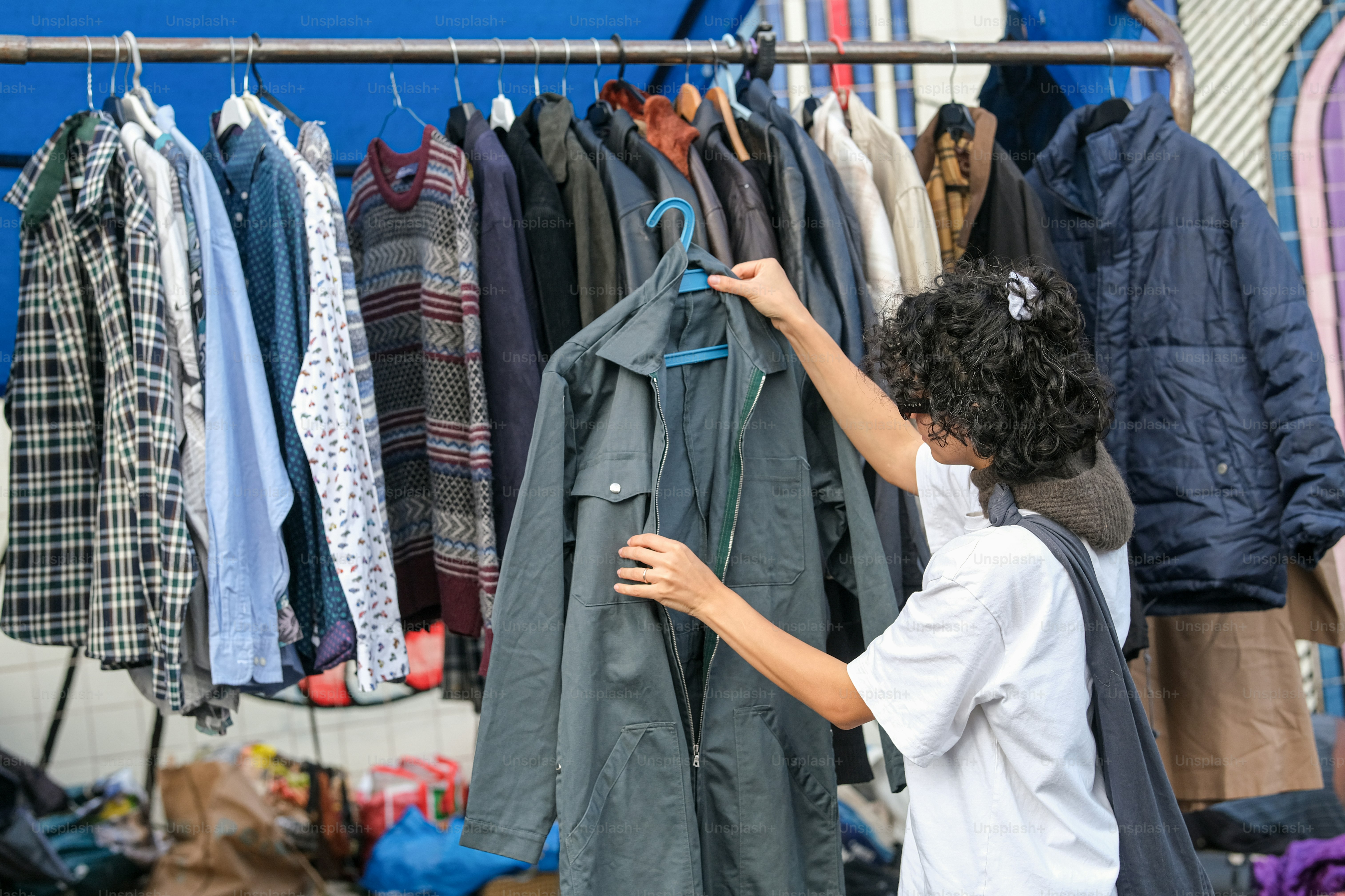 A young boy looking at clothes on a rack
