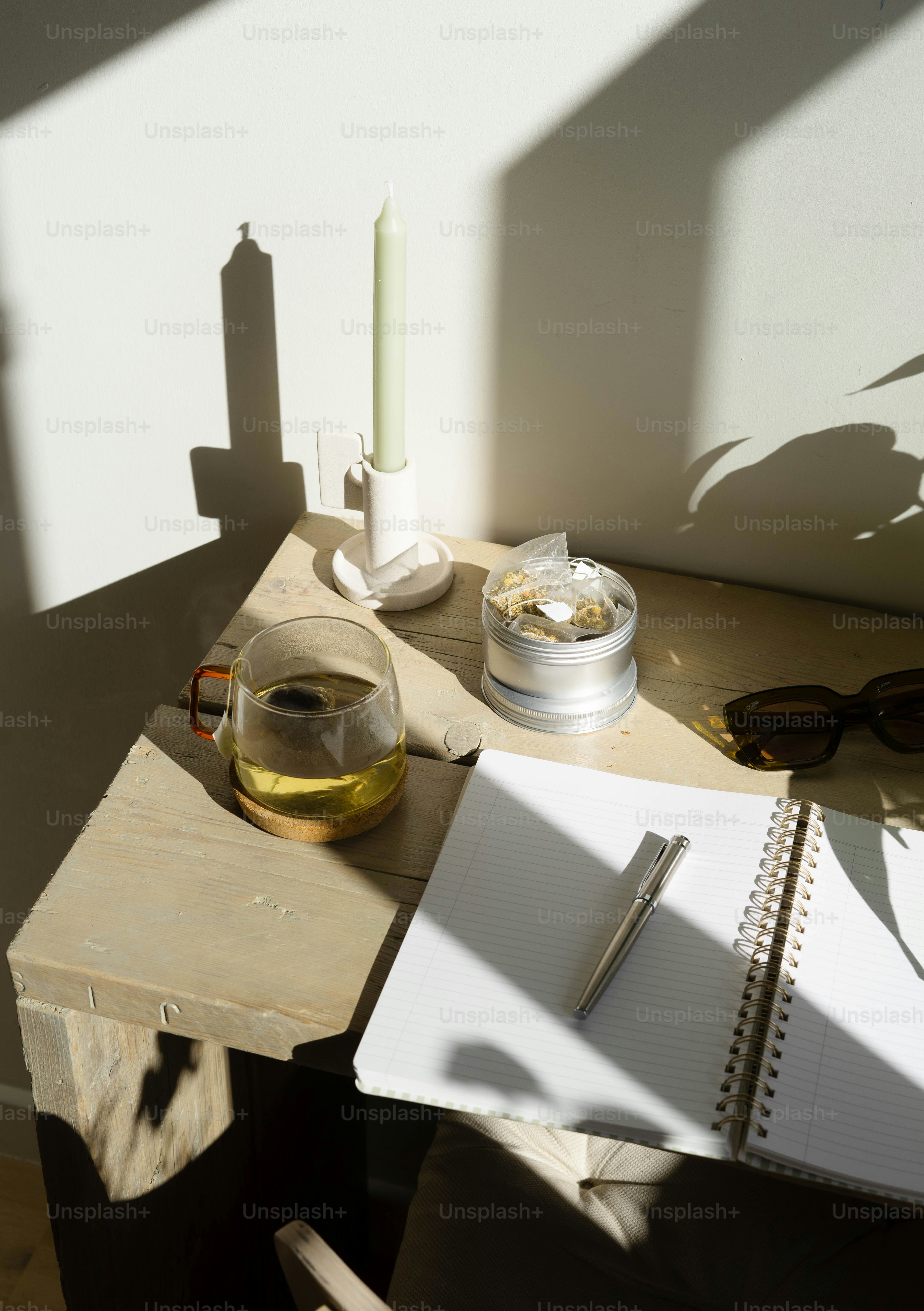 A wooden table topped with a notebook and a glass of wine