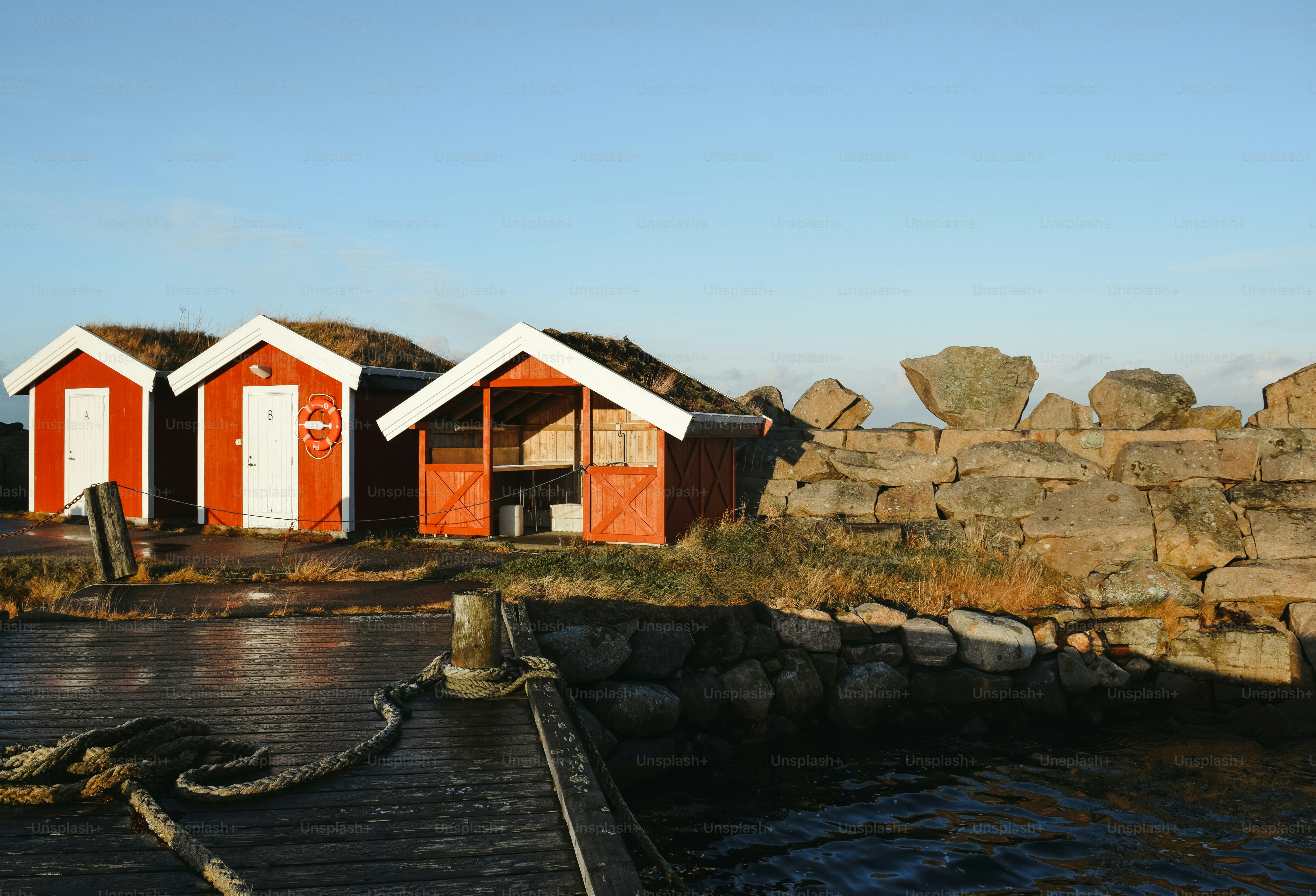 A row of red and white beach huts next to a body of water