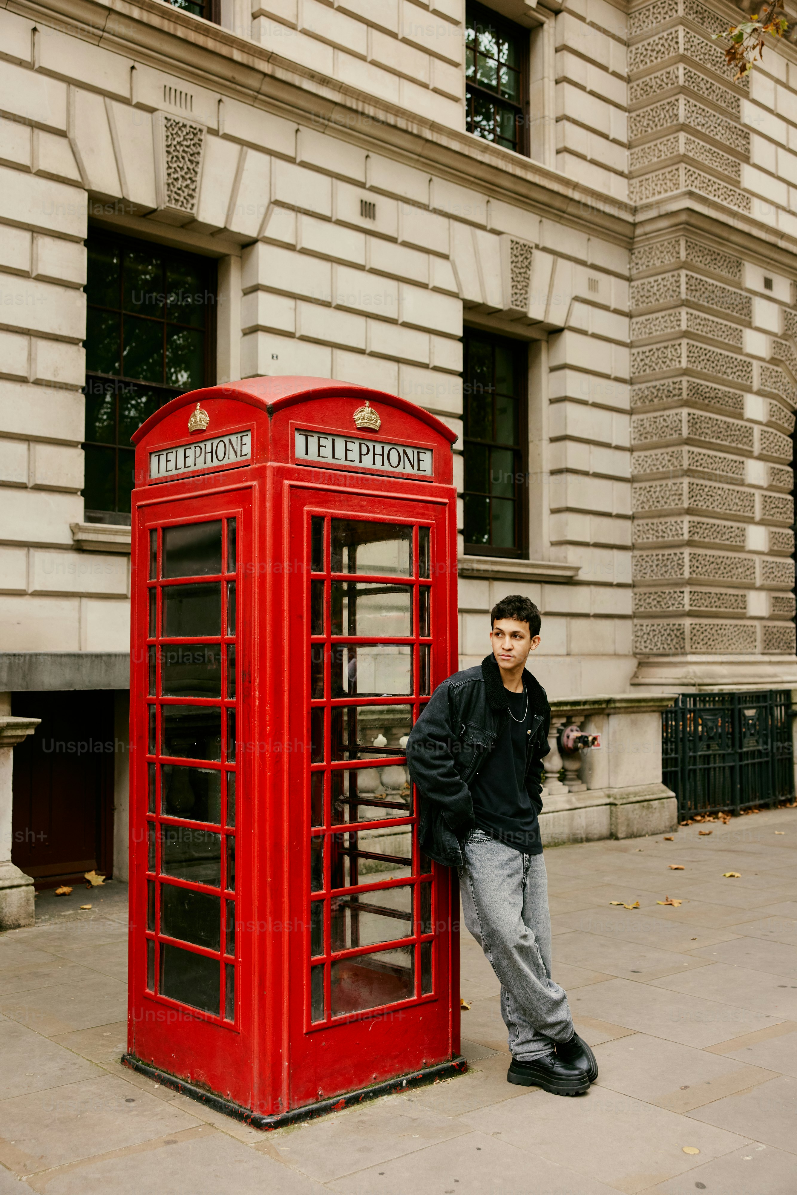 A man standing next to a red phone booth