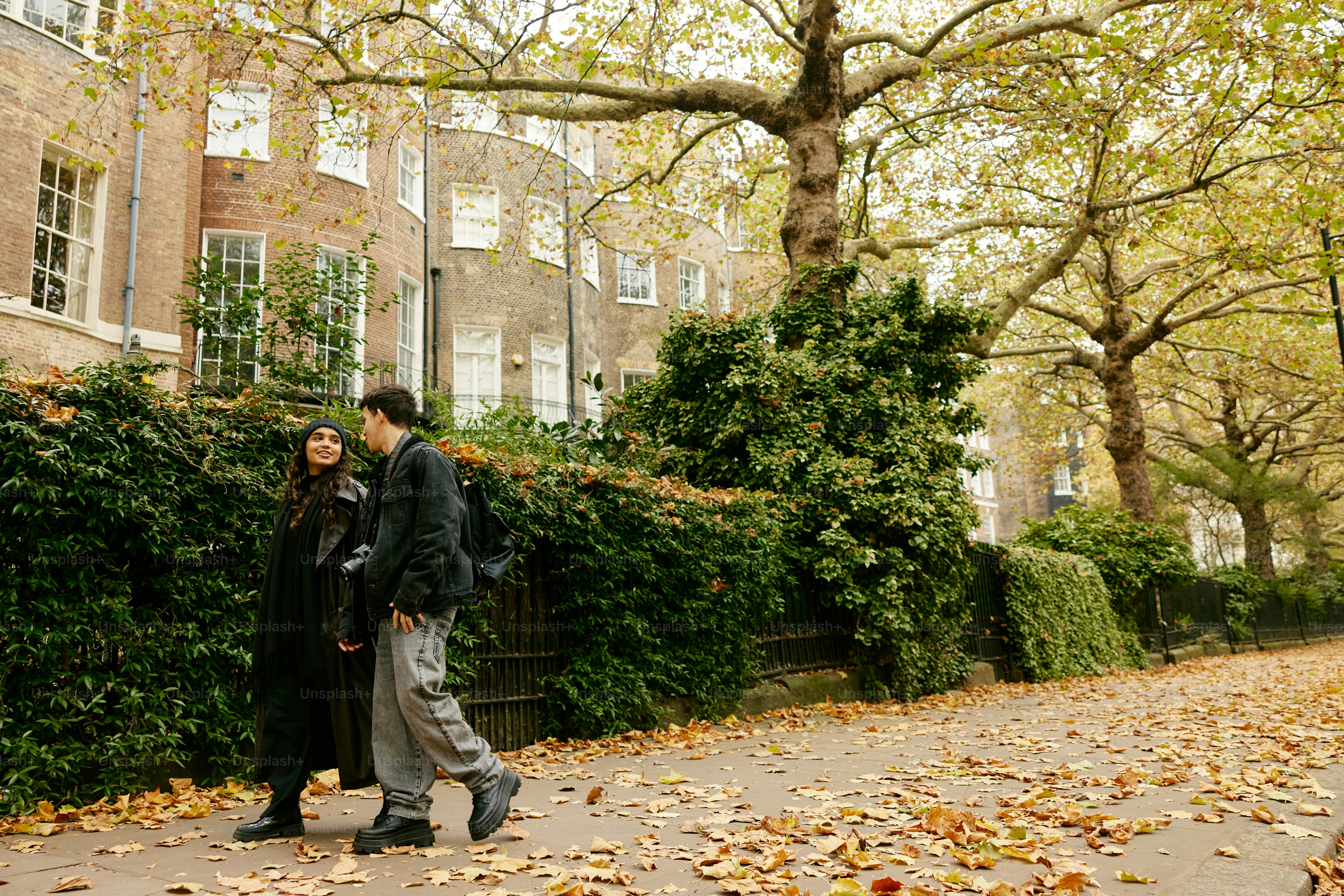 A man and a woman walking down a leaf covered street