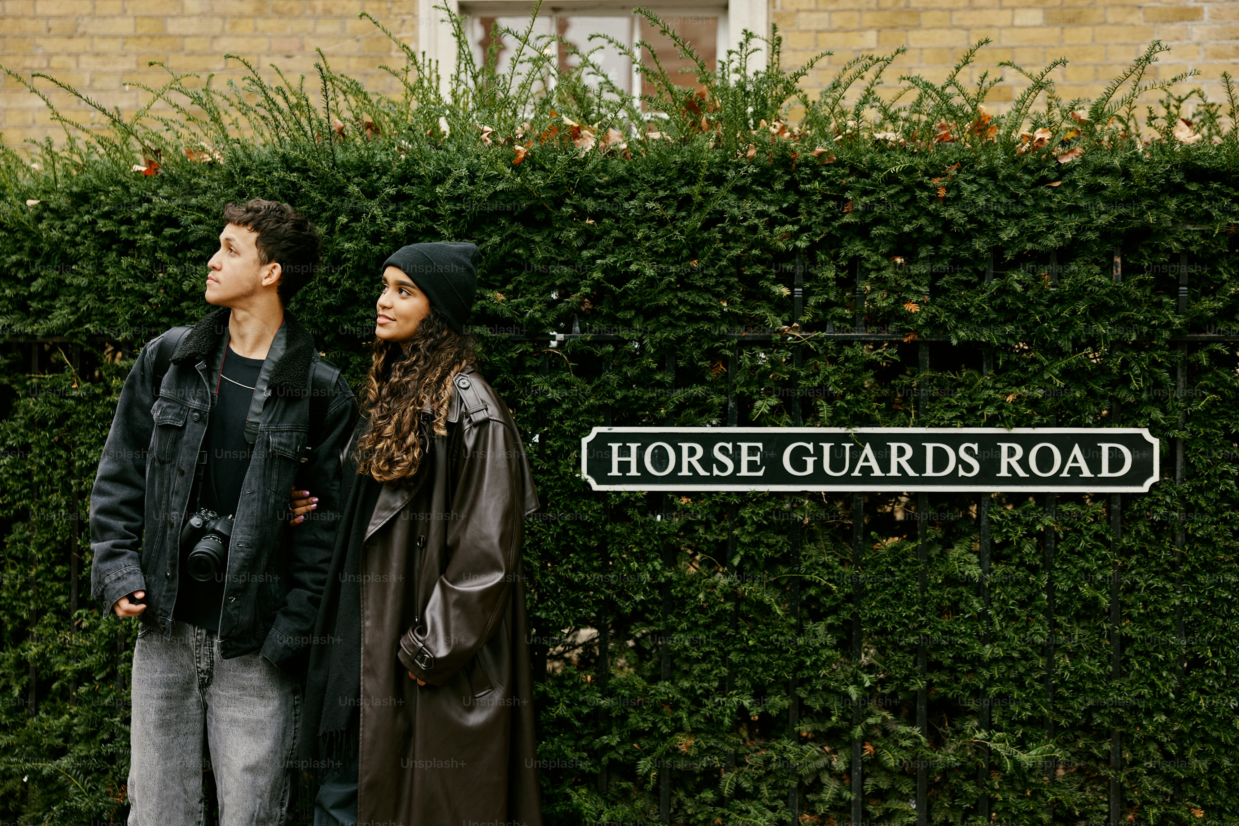 A man and a woman standing in front of a hedge
