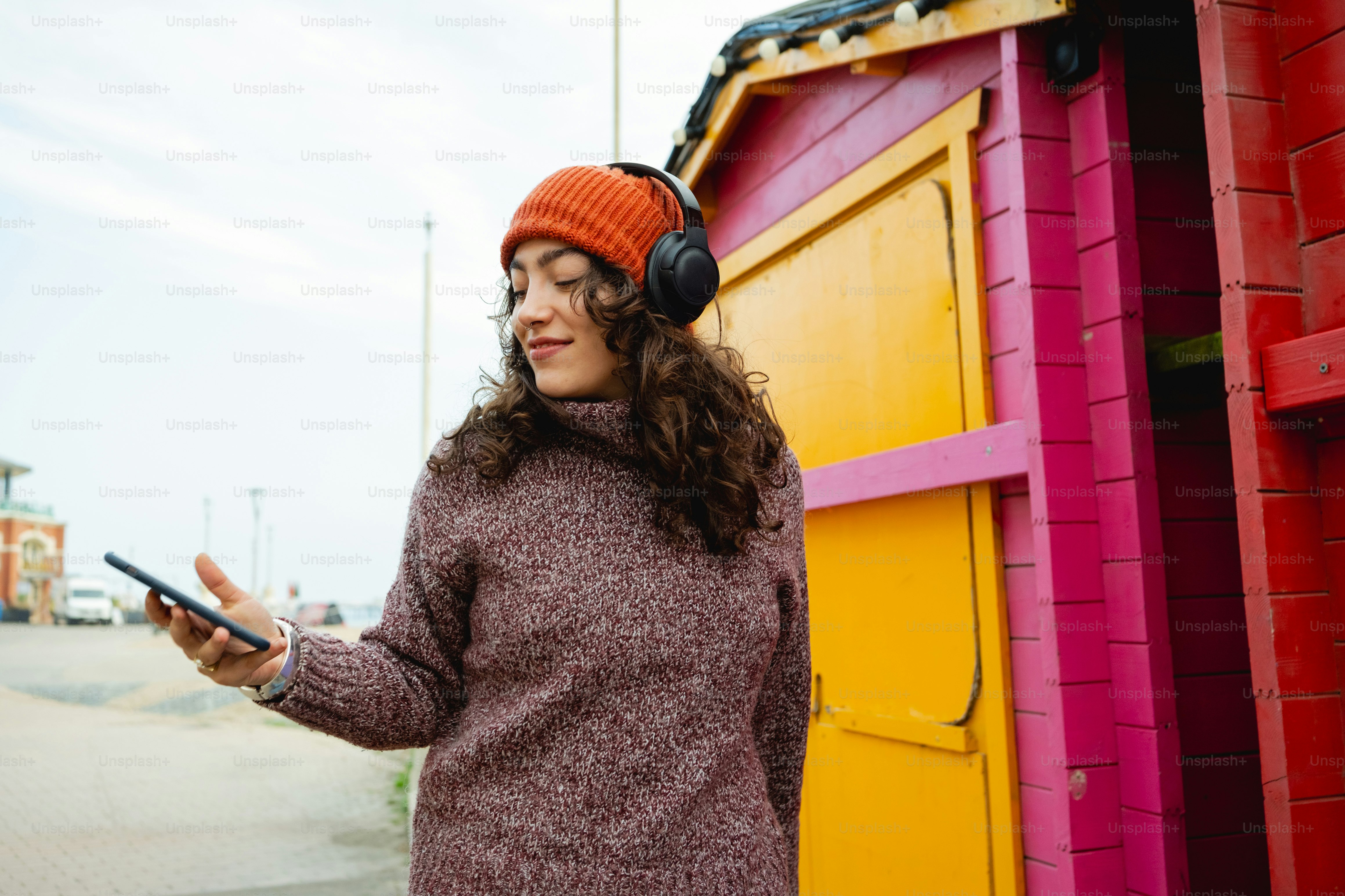 A woman wearing headphones standing in front of a building