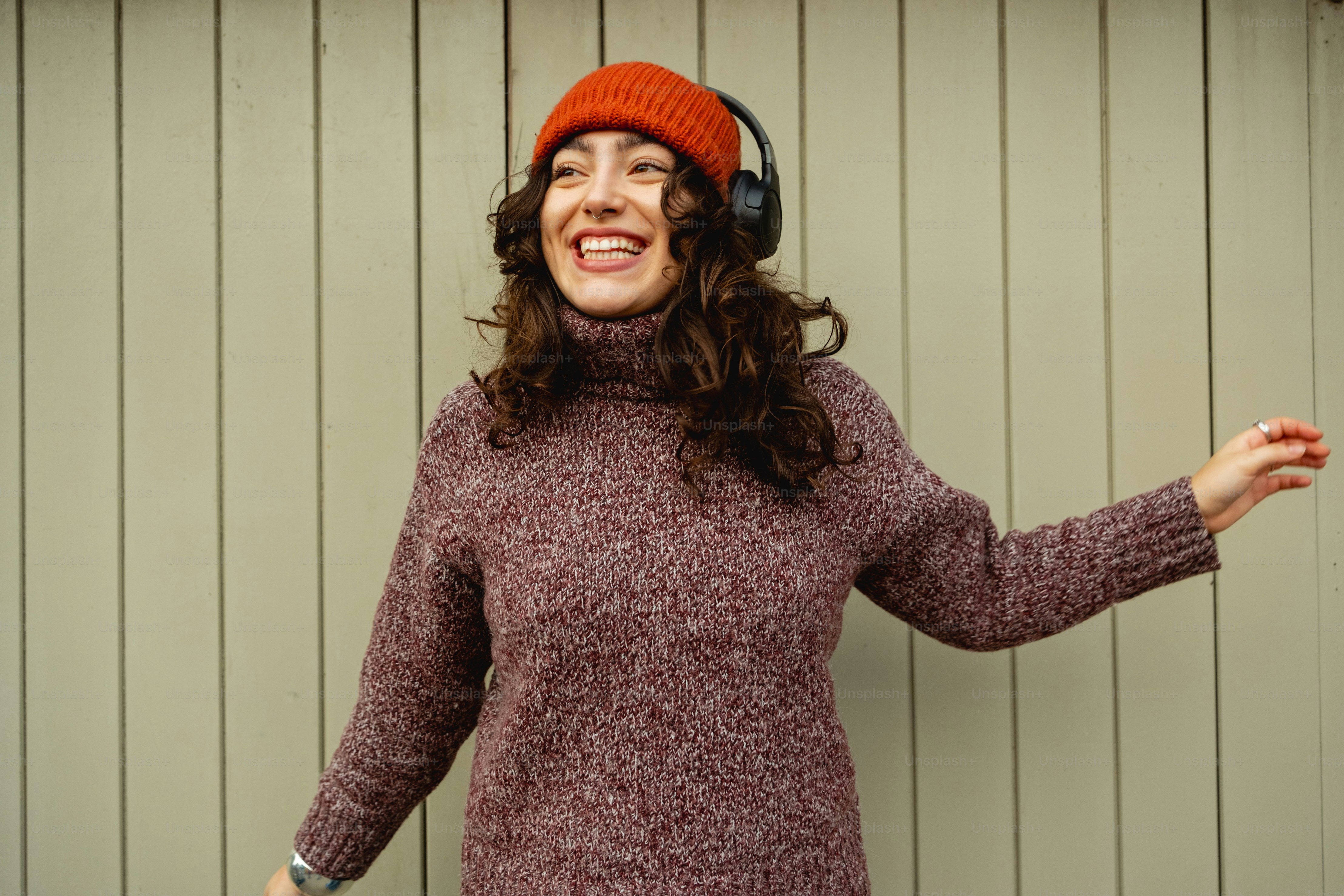 A woman wearing headphones standing in front of a wall