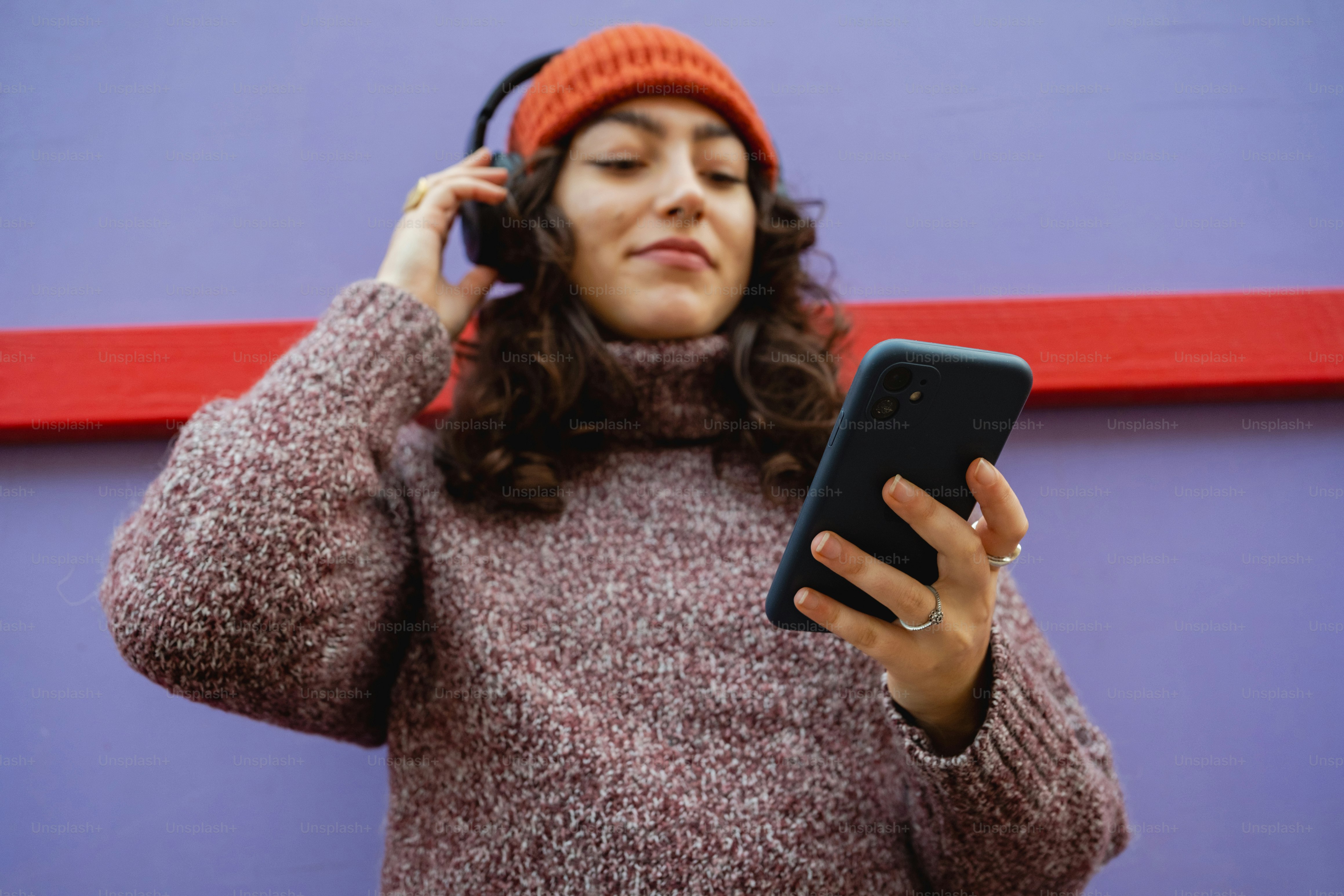 A woman wearing a beanie and using a cell phone