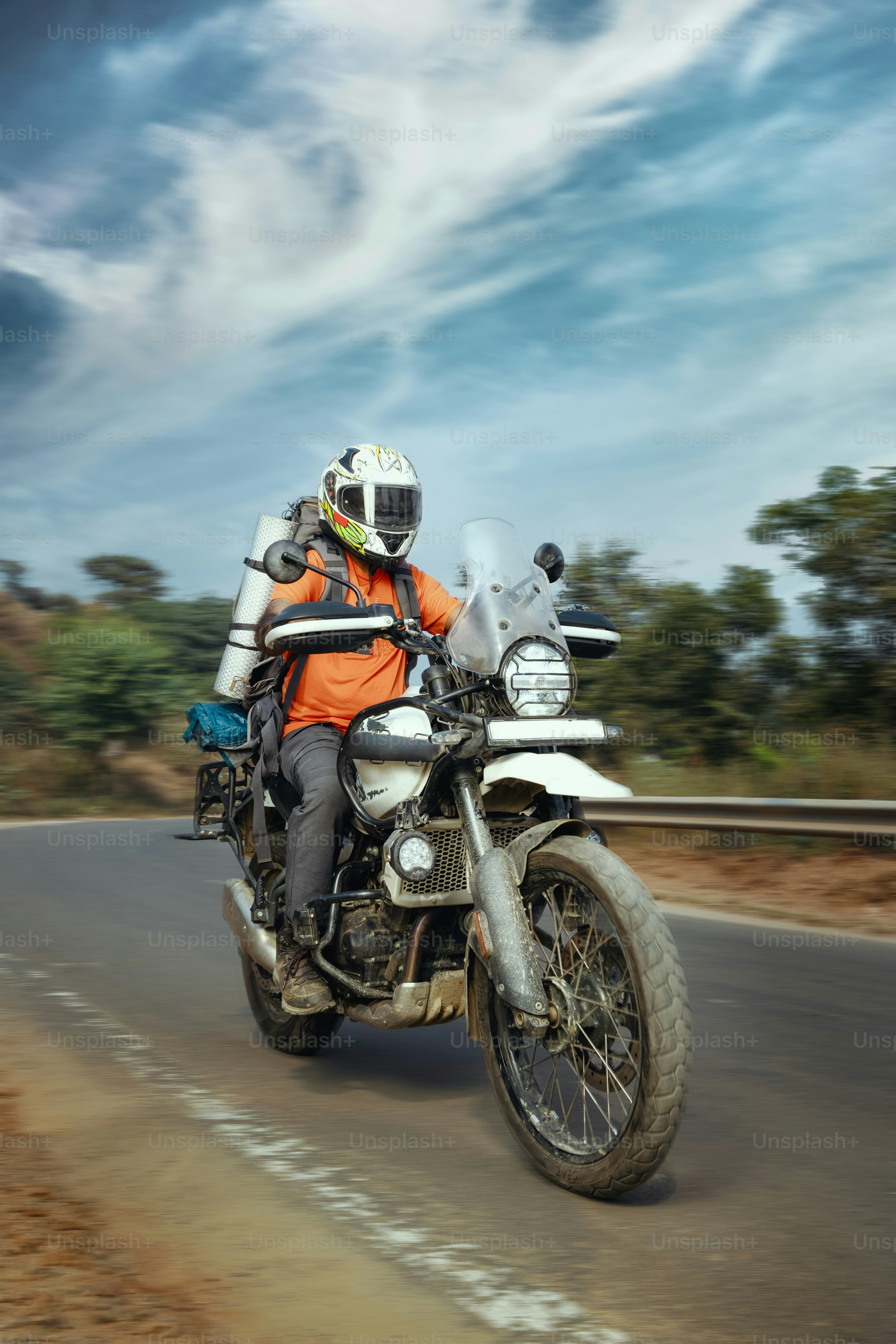 A man riding on the back of a motorcycle down a road photo – Travel ...