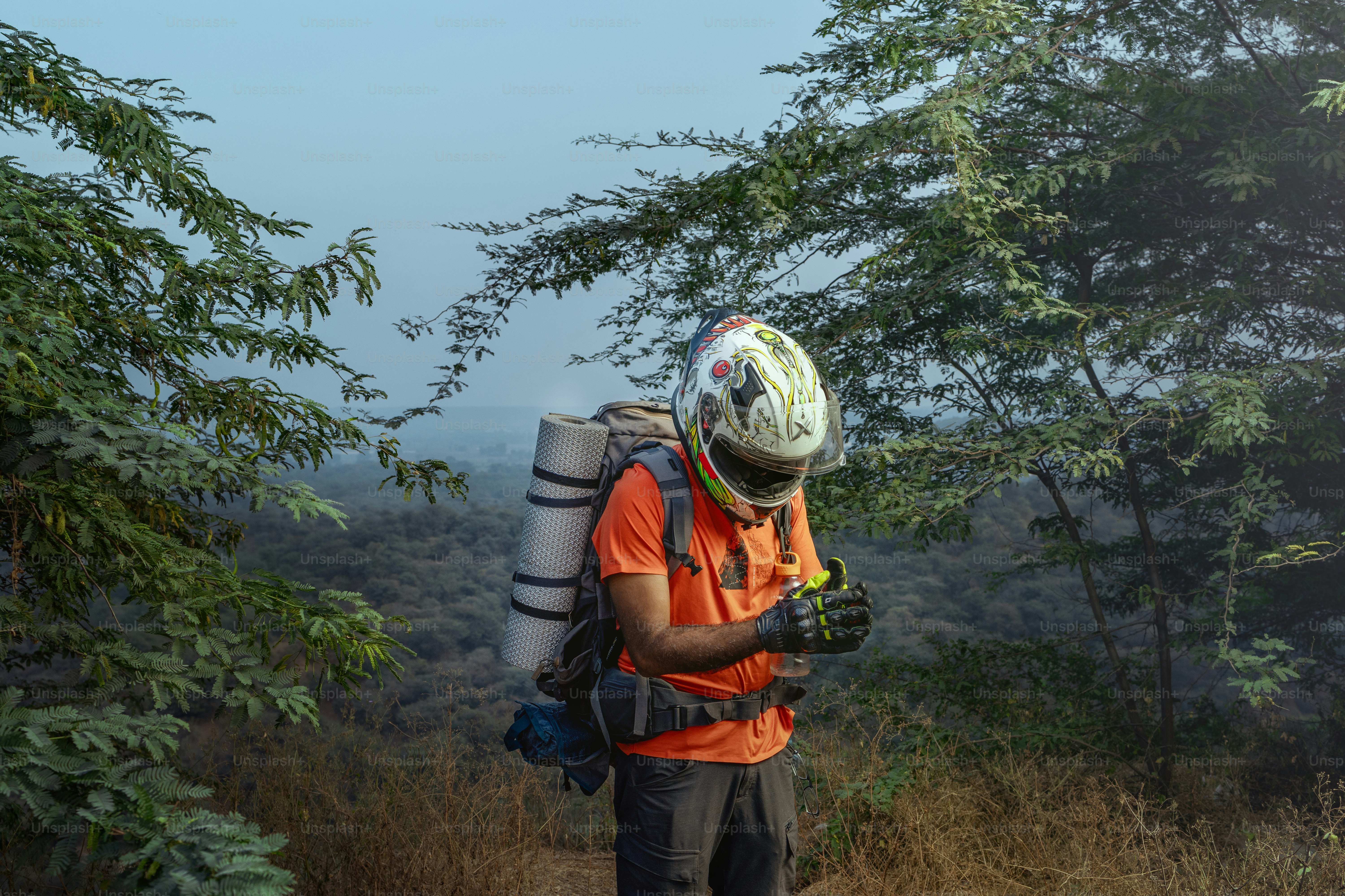 A man with a backpack and a helmet is walking in the woods