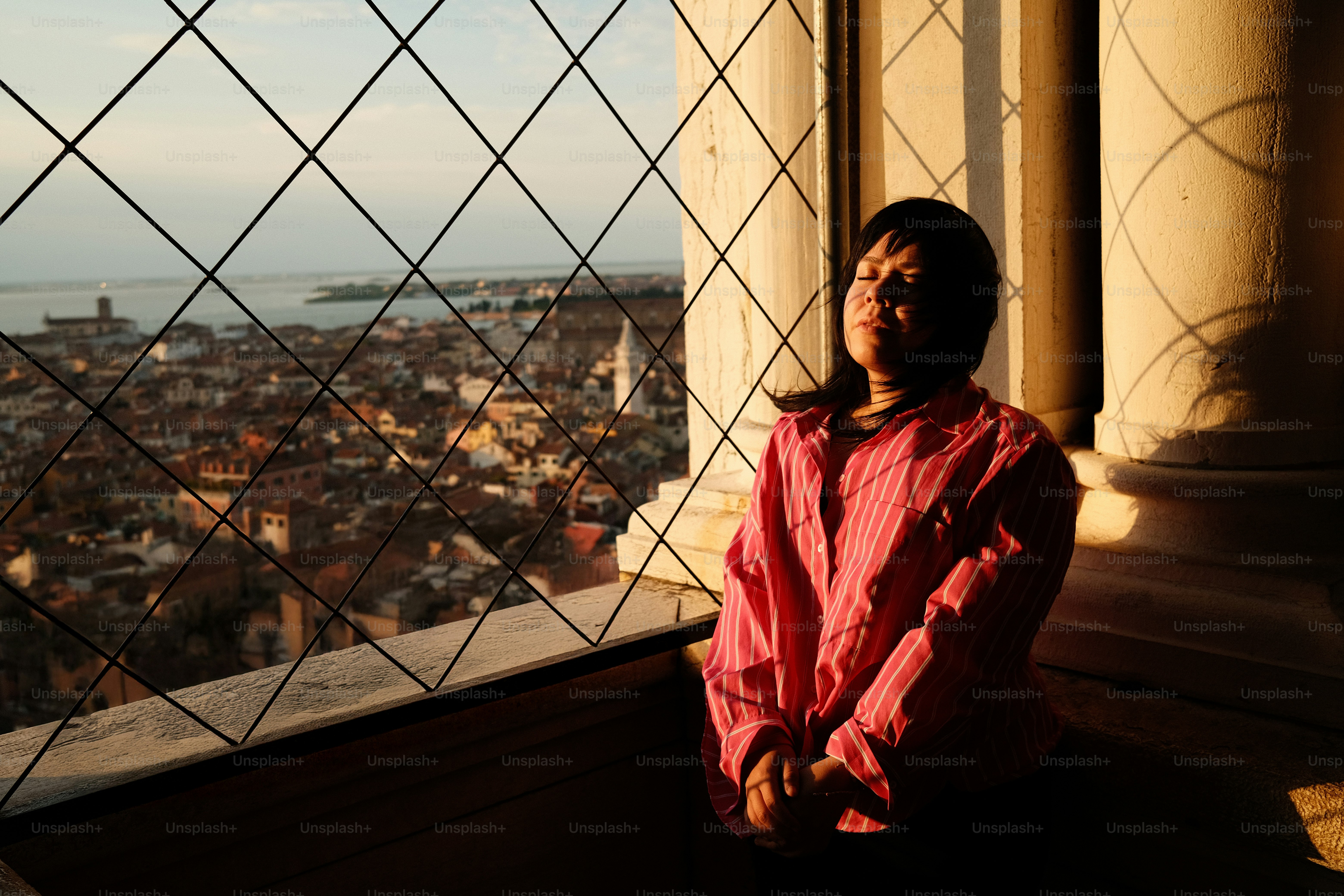 A man standing in front of a window with a view of a city photo ...