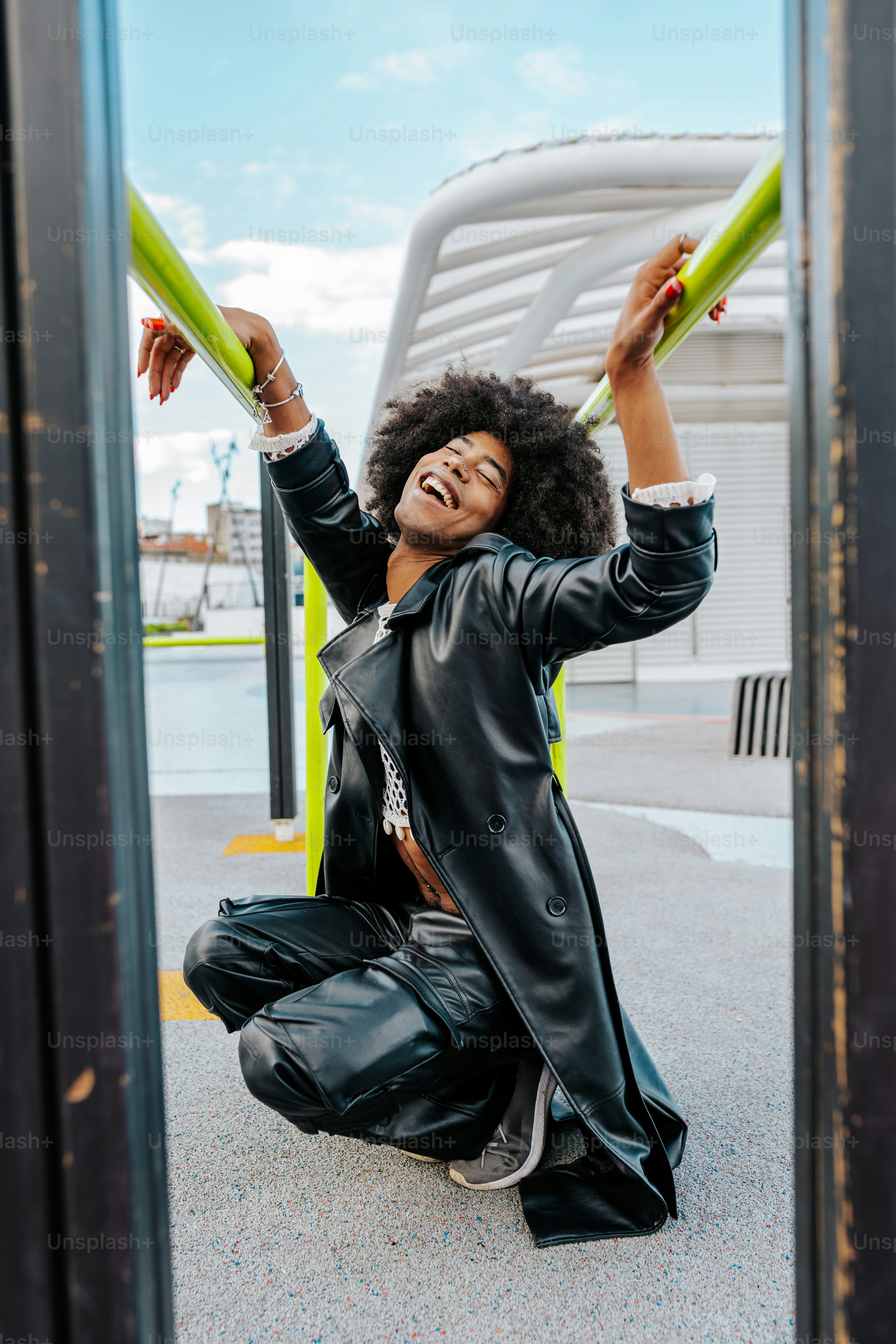 A woman in a black leather jacket and black pants sitting on the ground