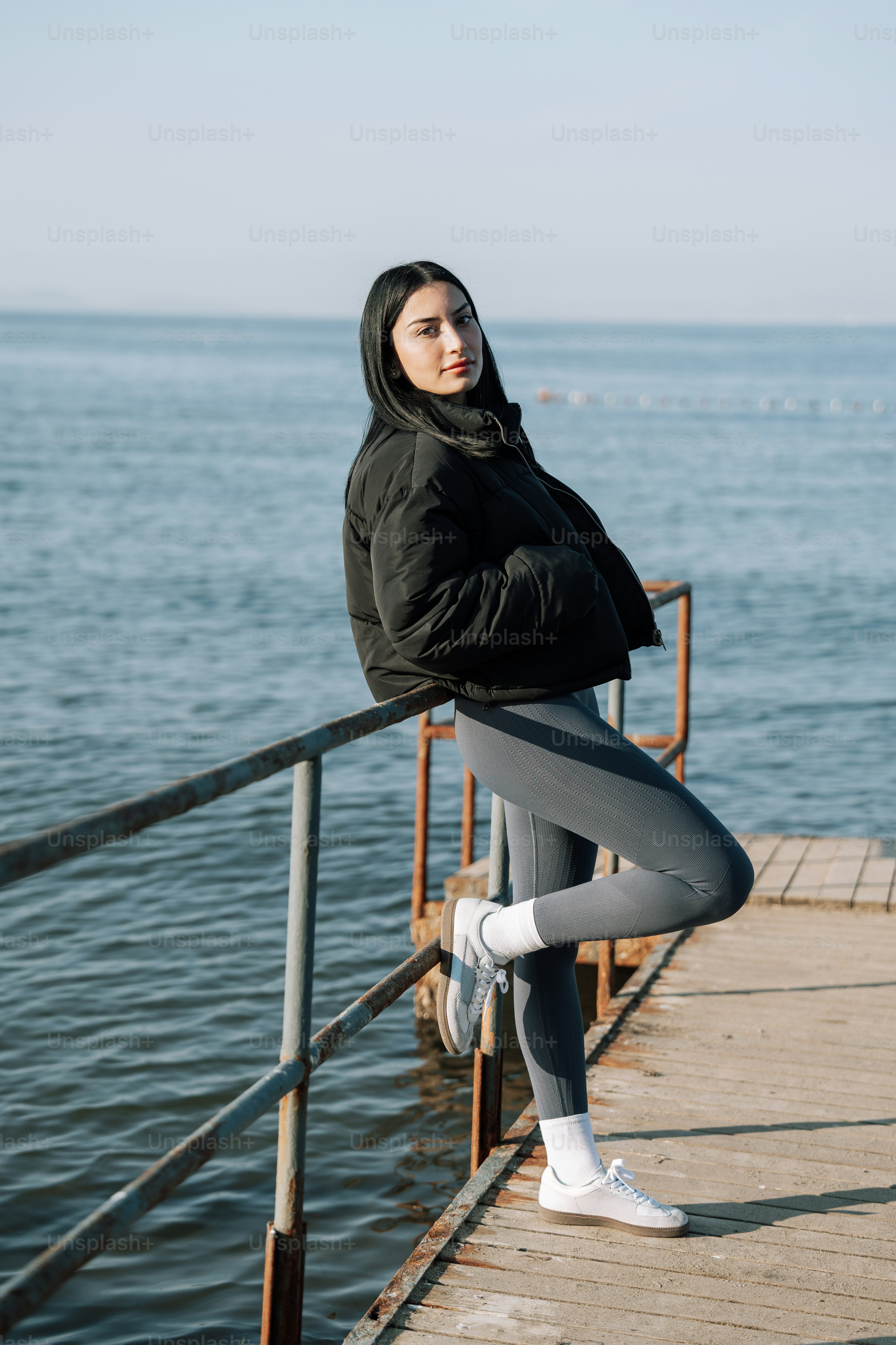 Eine Frau, die auf einem Pier neben dem Meer steht