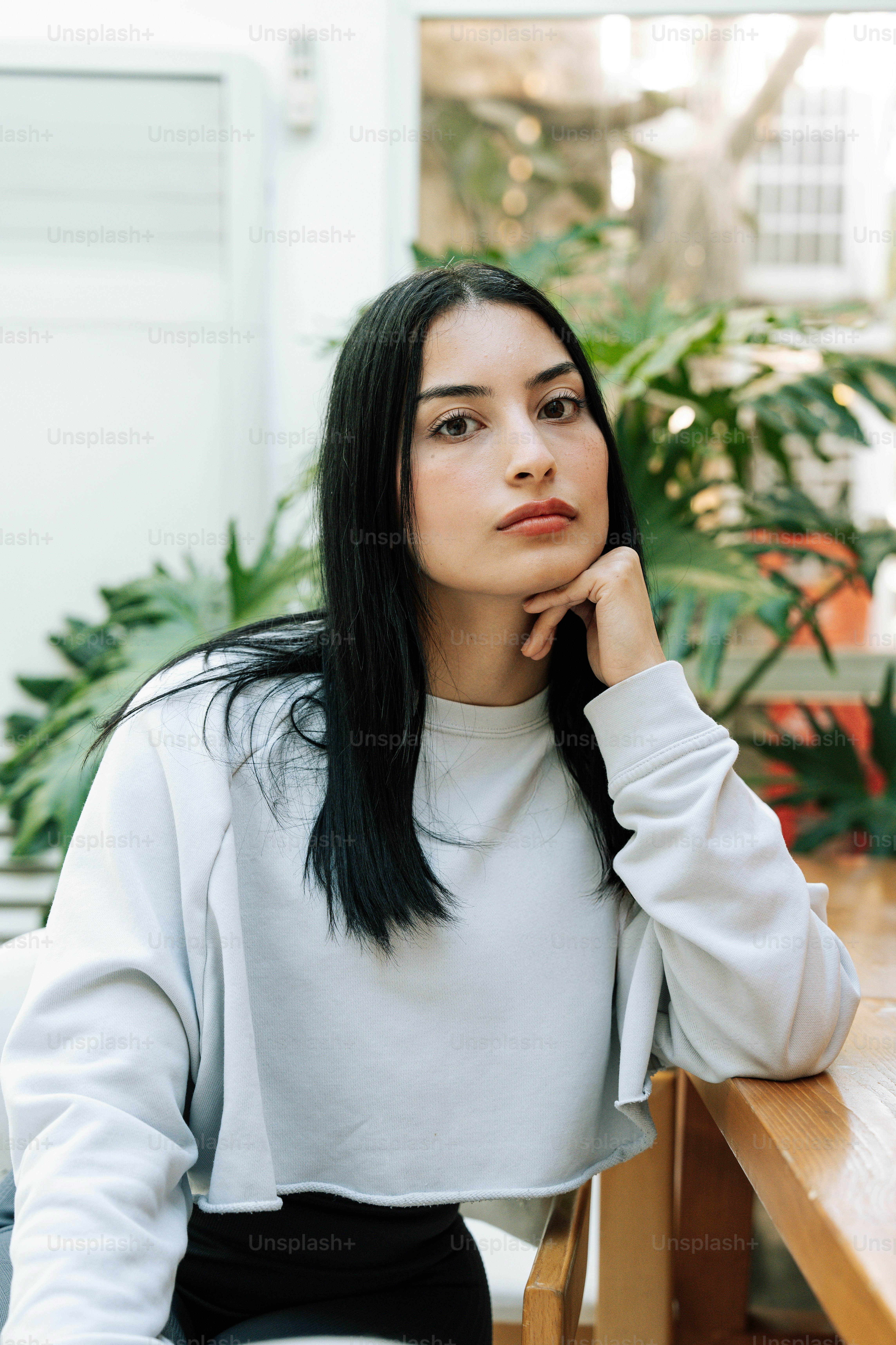 A woman sitting at a table with her hand on her chin photo – Profile ...