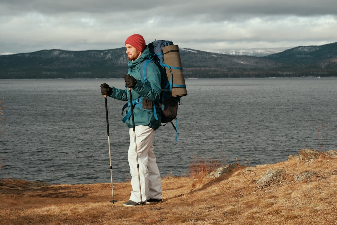 A man with a backpack and ski poles standing on a hill