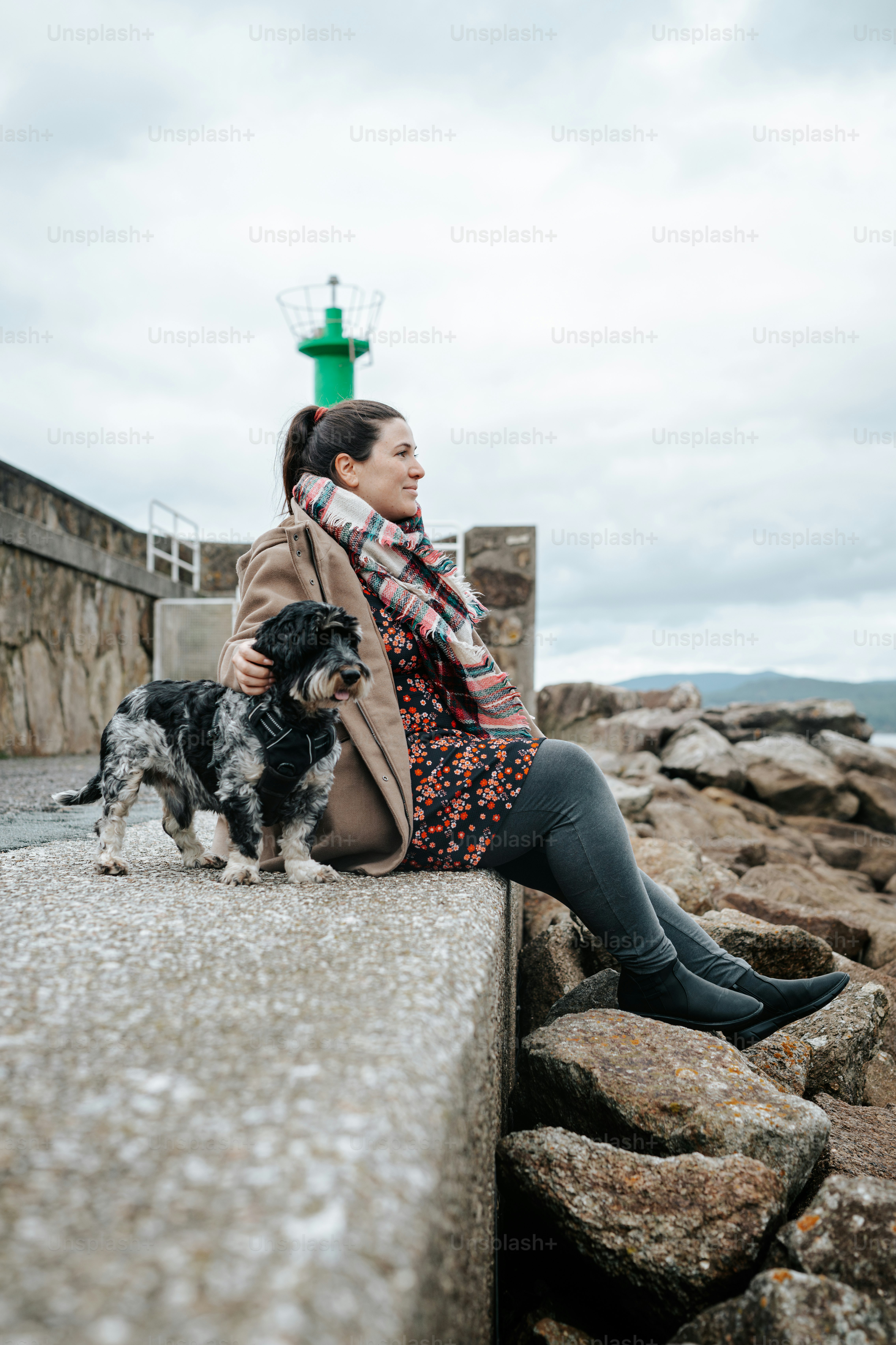 A woman sitting on a ledge next to a dog