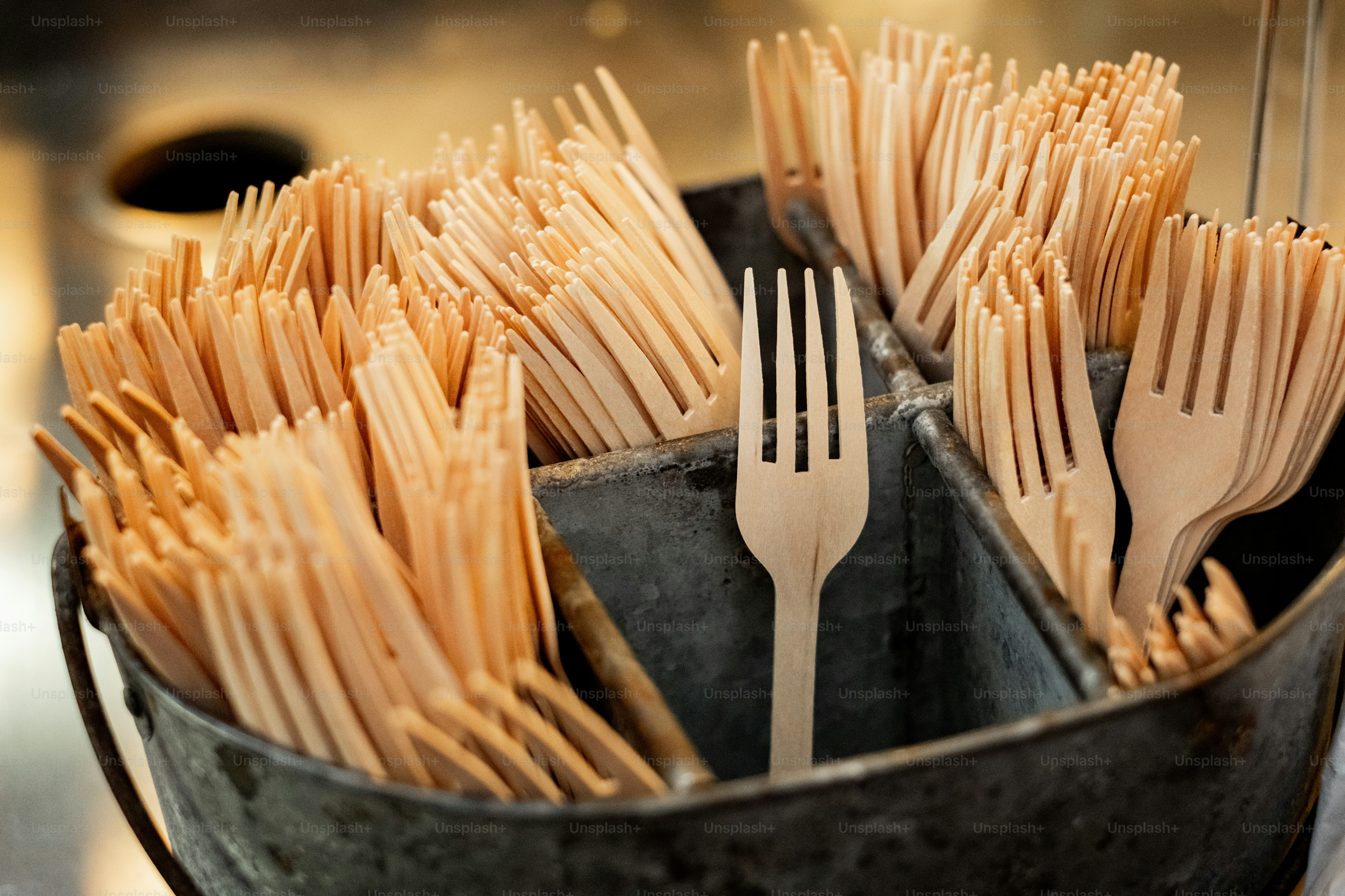 Ein Eimer voller Gabeln und Löffel auf einem Tisch