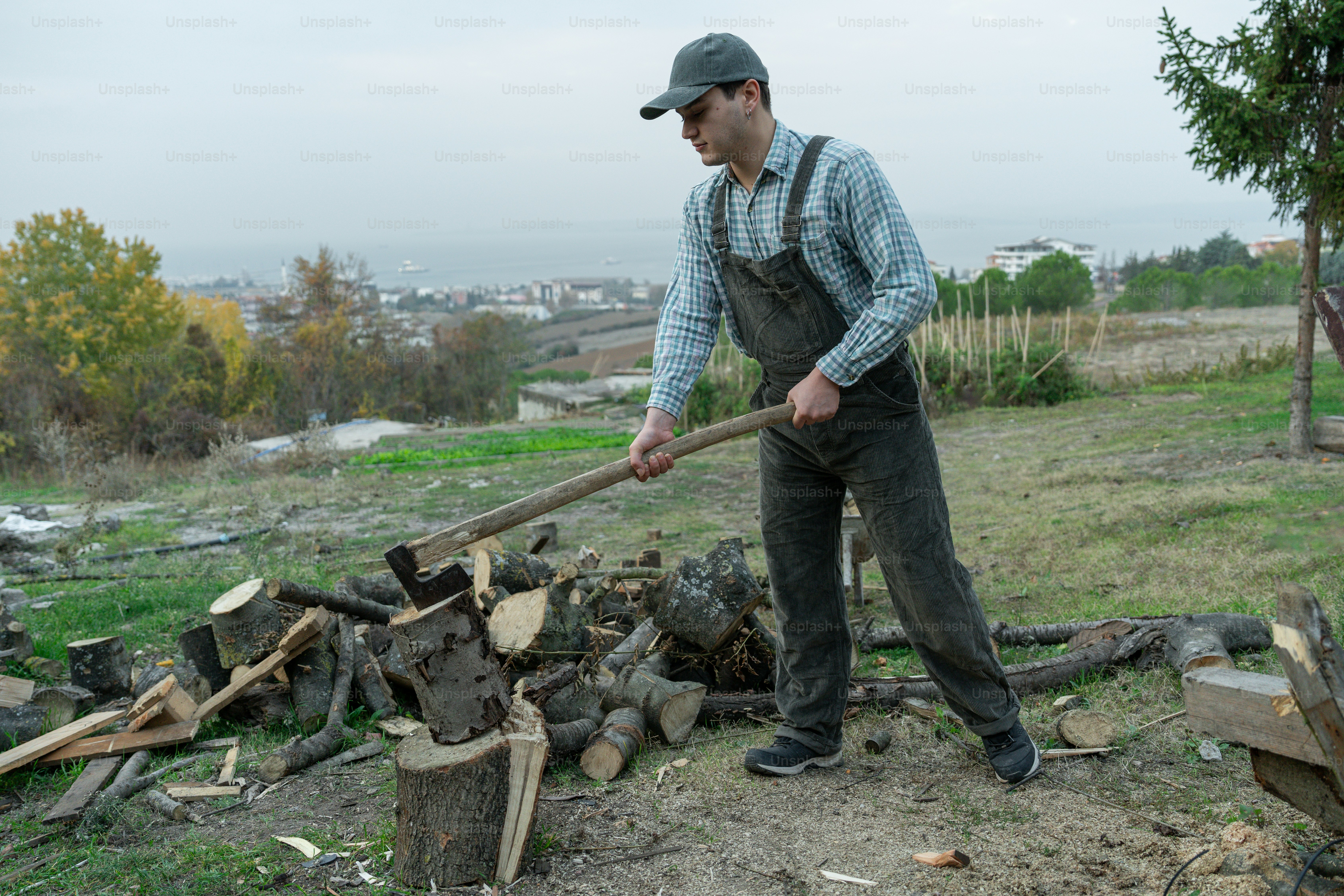 Un hombre sosteniendo un palo cerca de una pila de madera