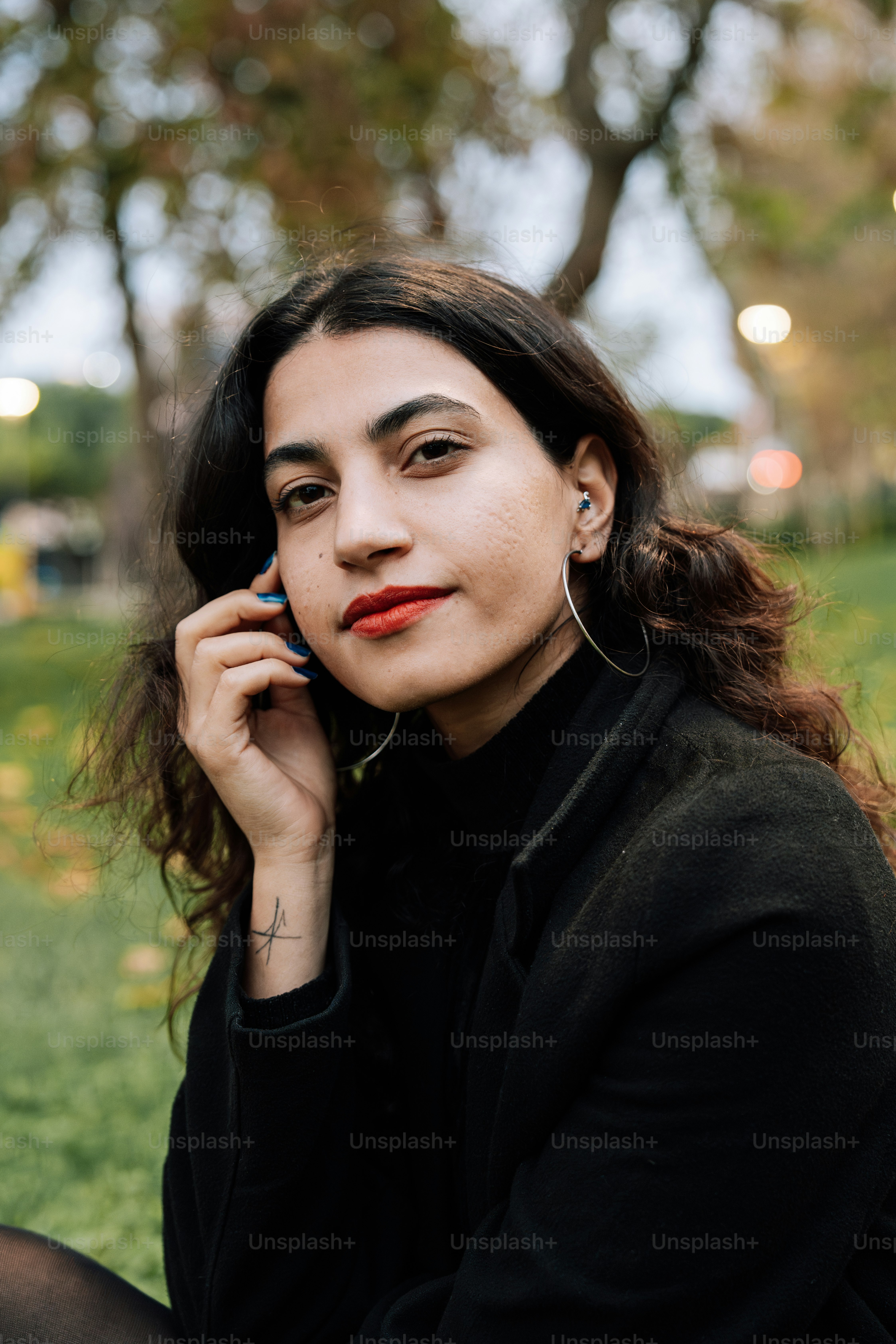 A woman sitting in the grass talking on a cell phone