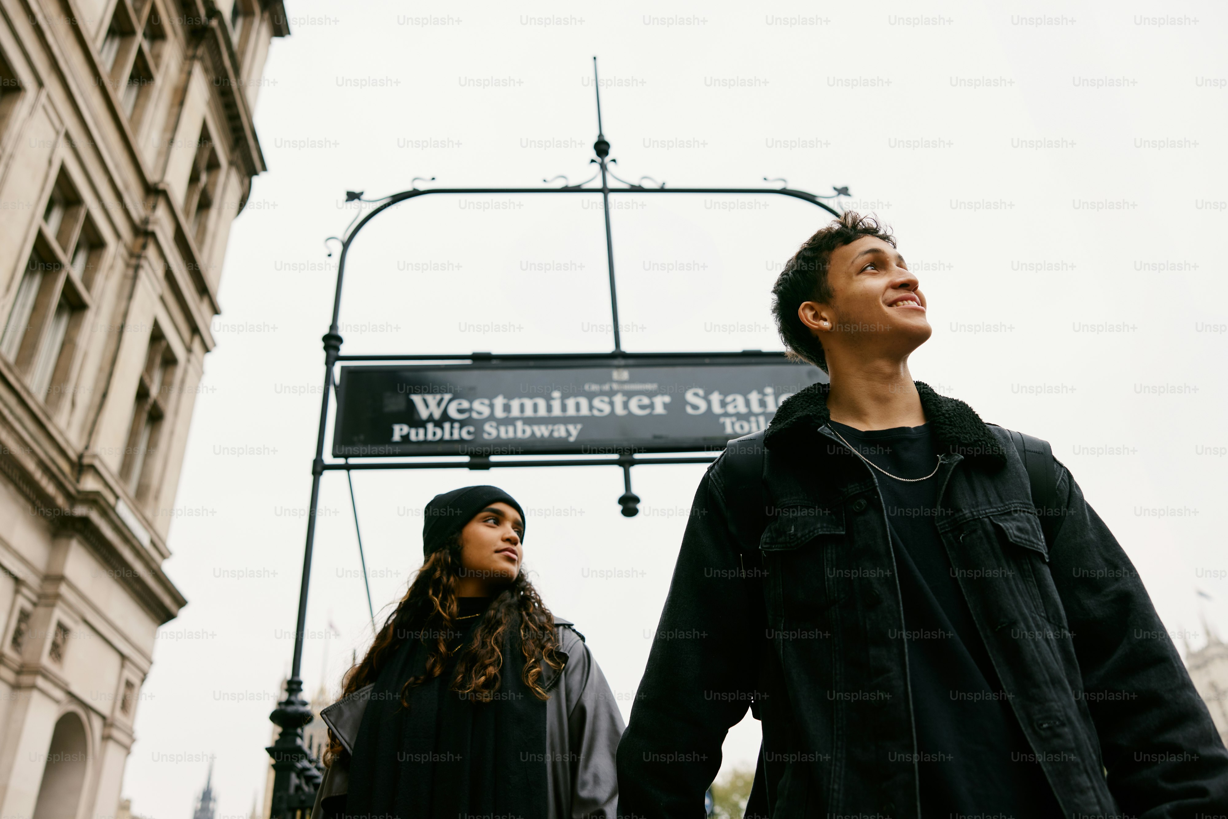 A man and a woman standing under a street sign