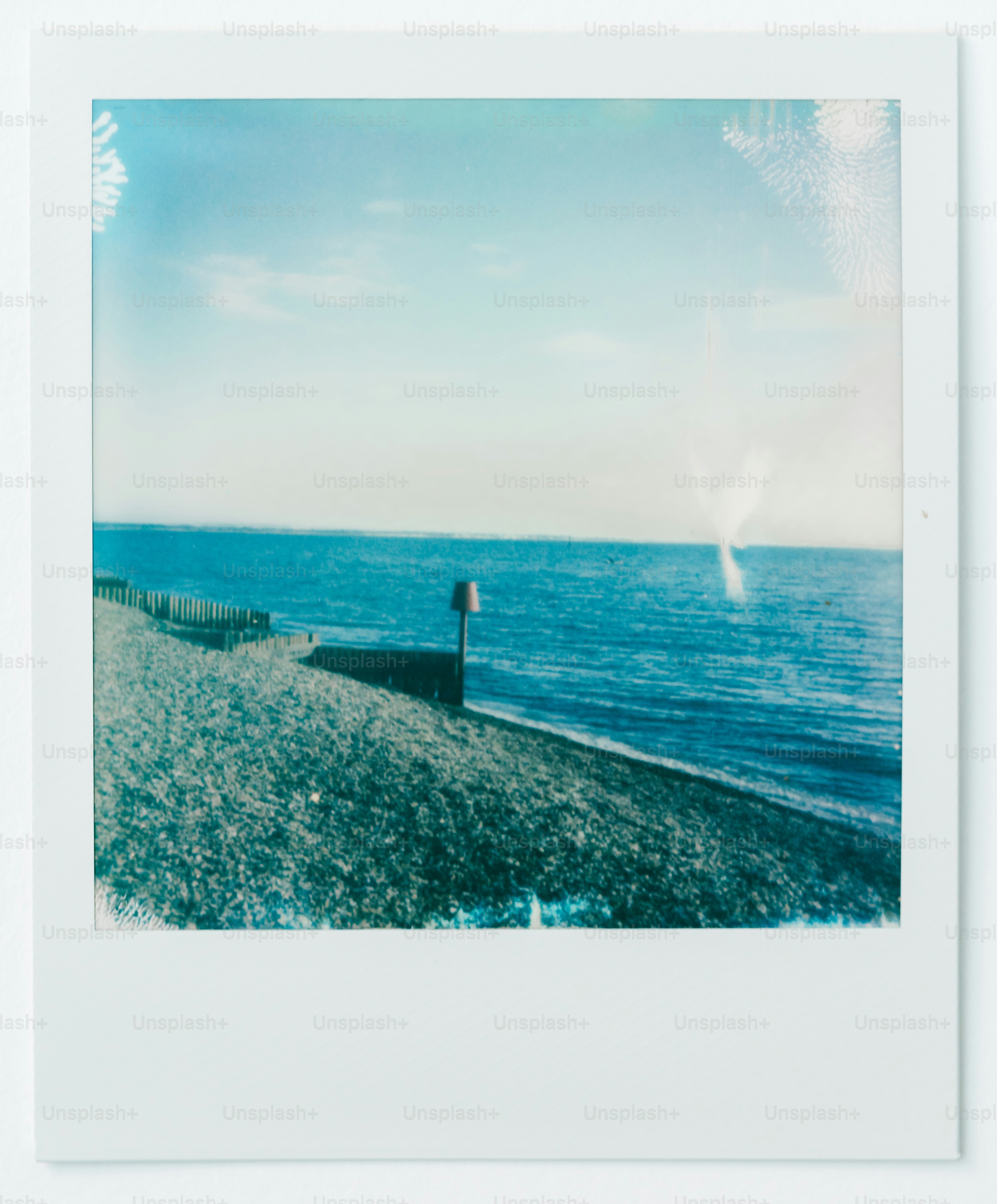 A polaroid photo of a beach with a person standing on it