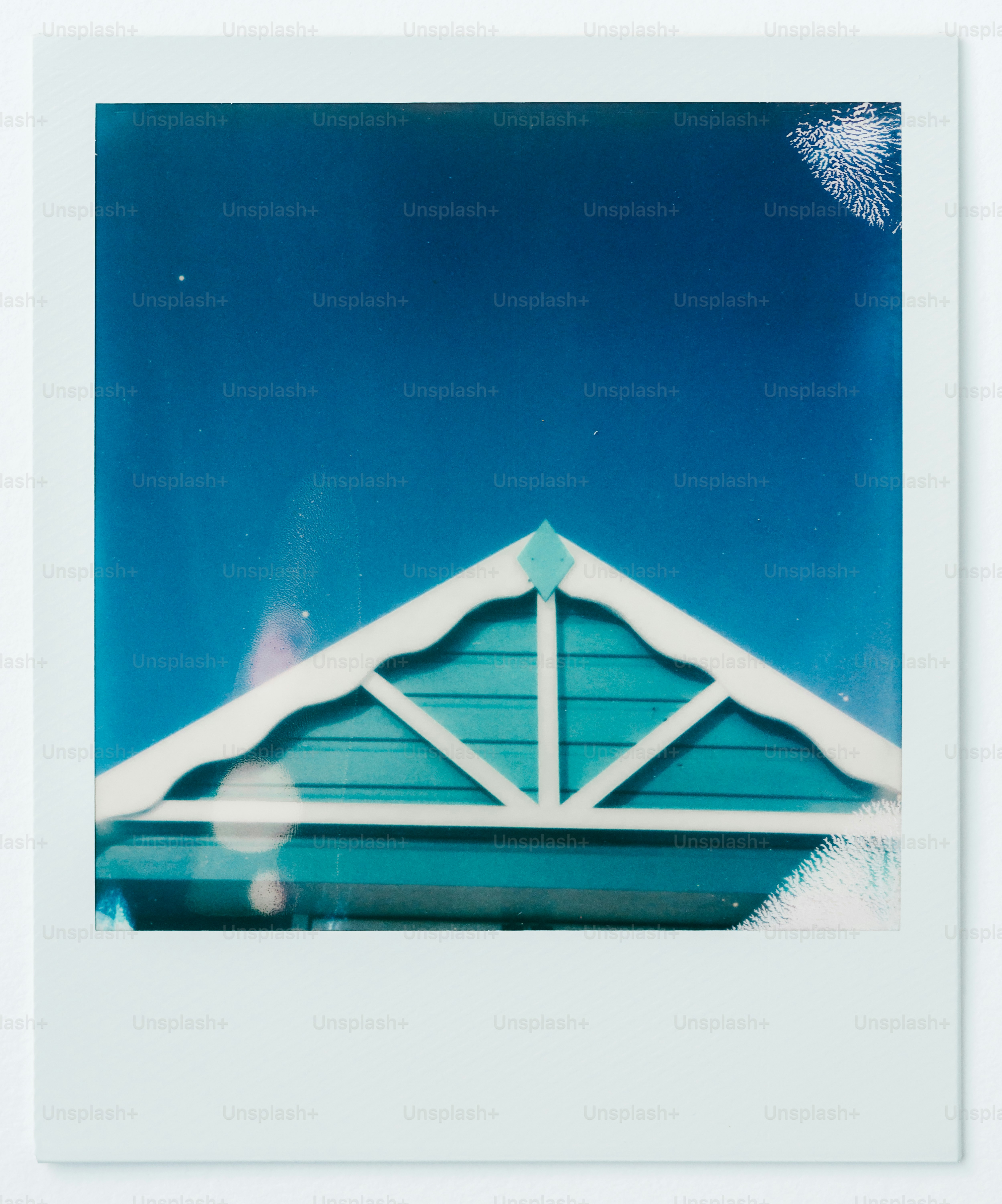 A polaroid photograph of a blue house with a white roof