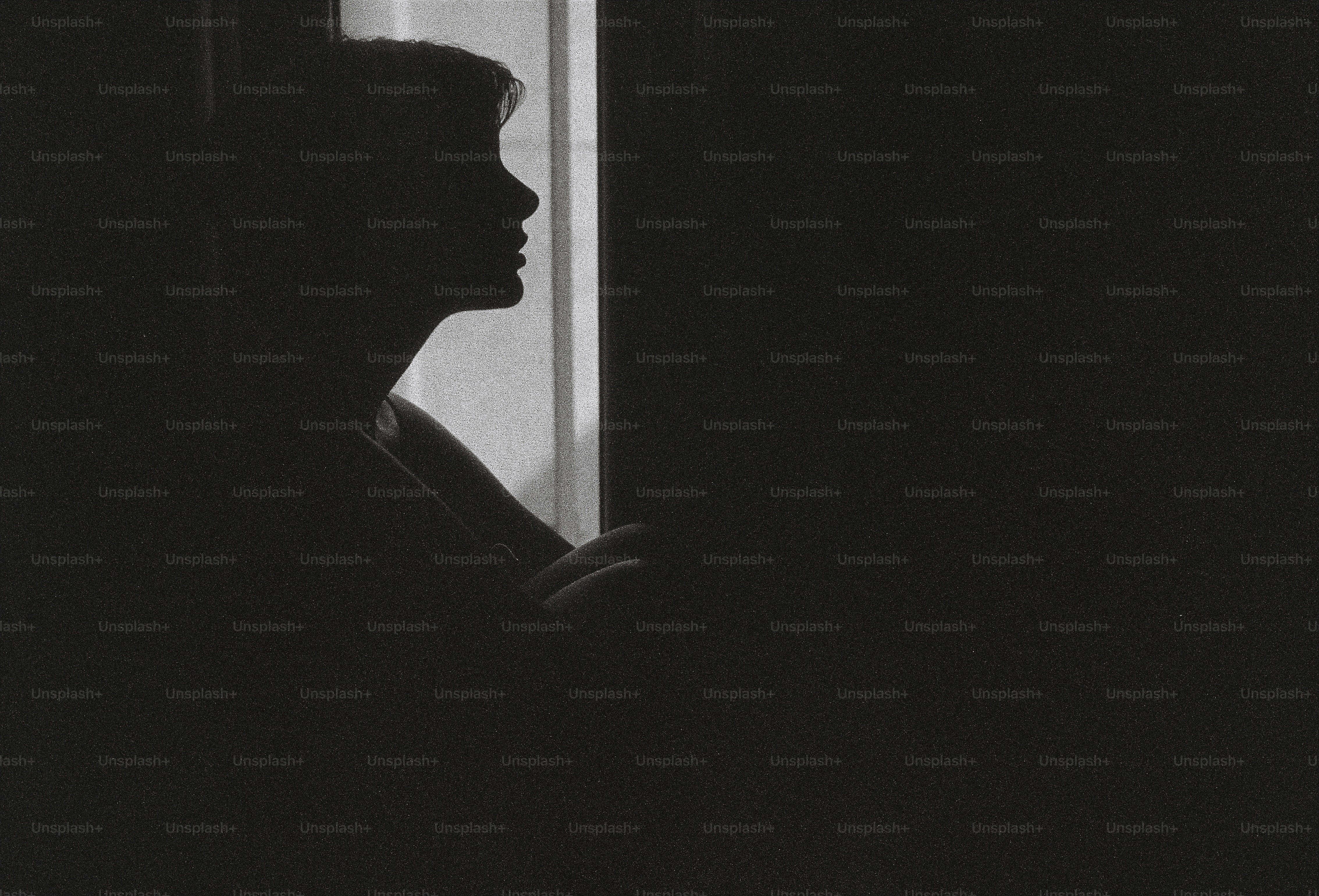 A black and white photo of a woman looking out a window