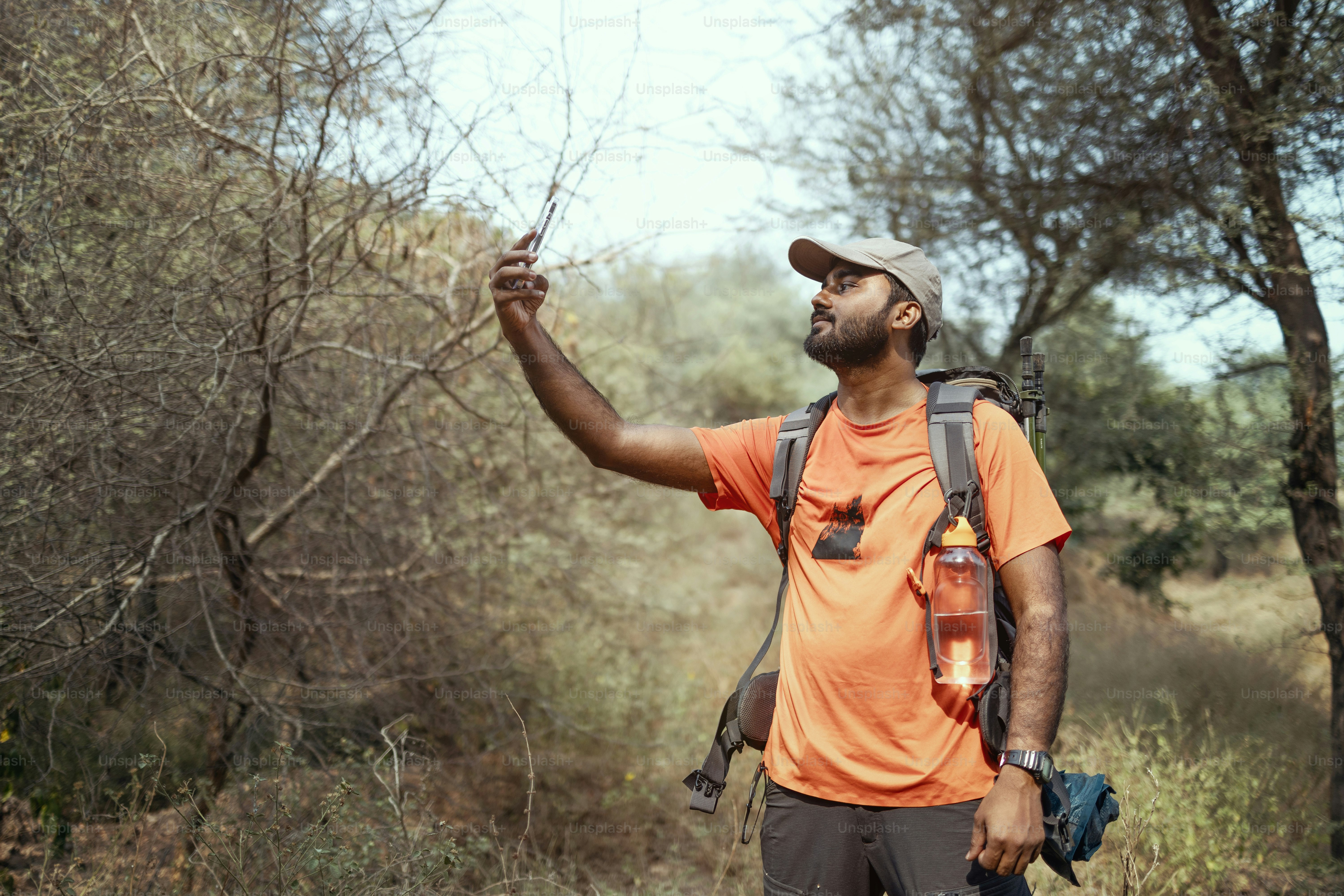 Un uomo con una maglietta arancione è in piedi nel bosco