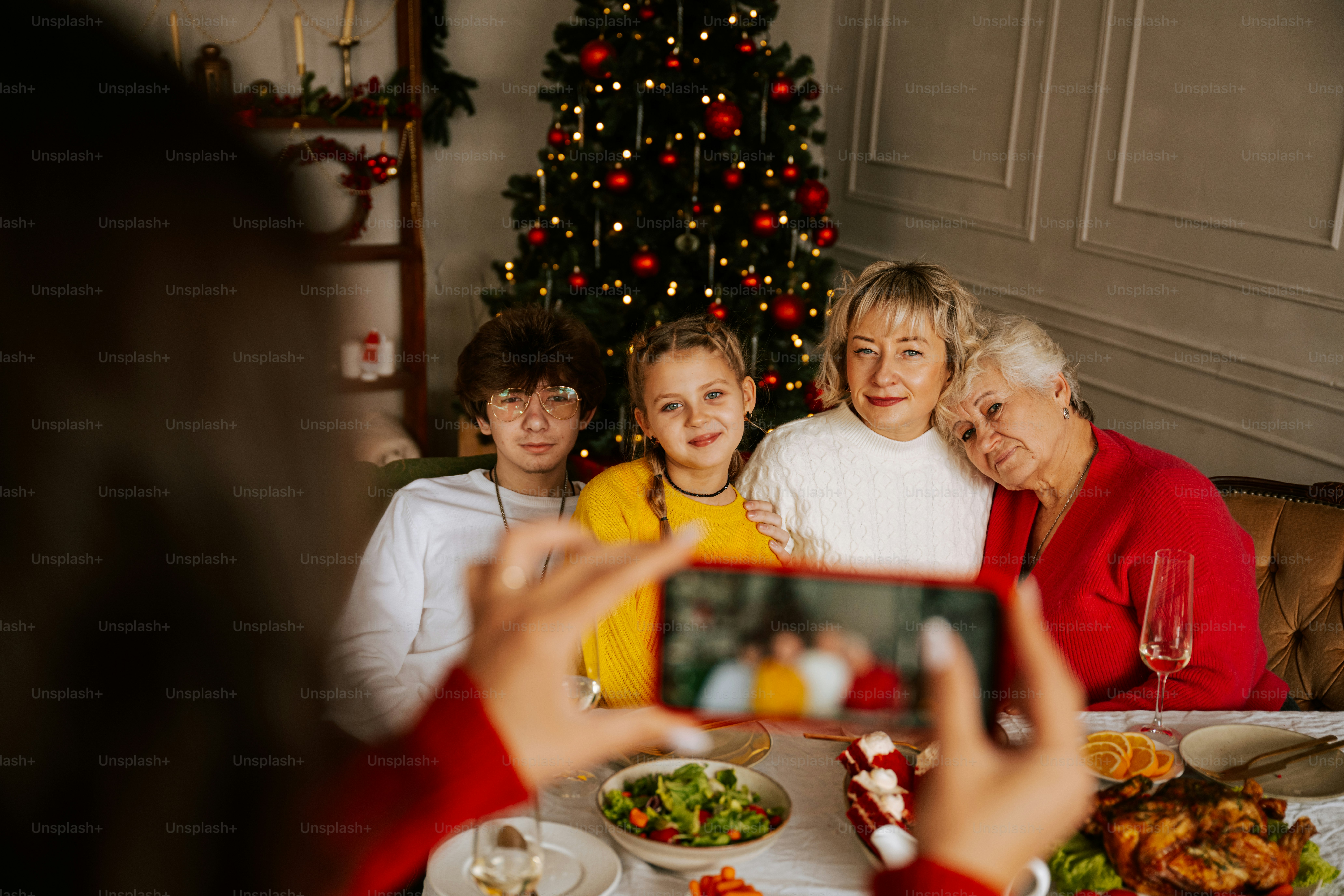 A group of people sitting around a table taking a picture of a christmas tree