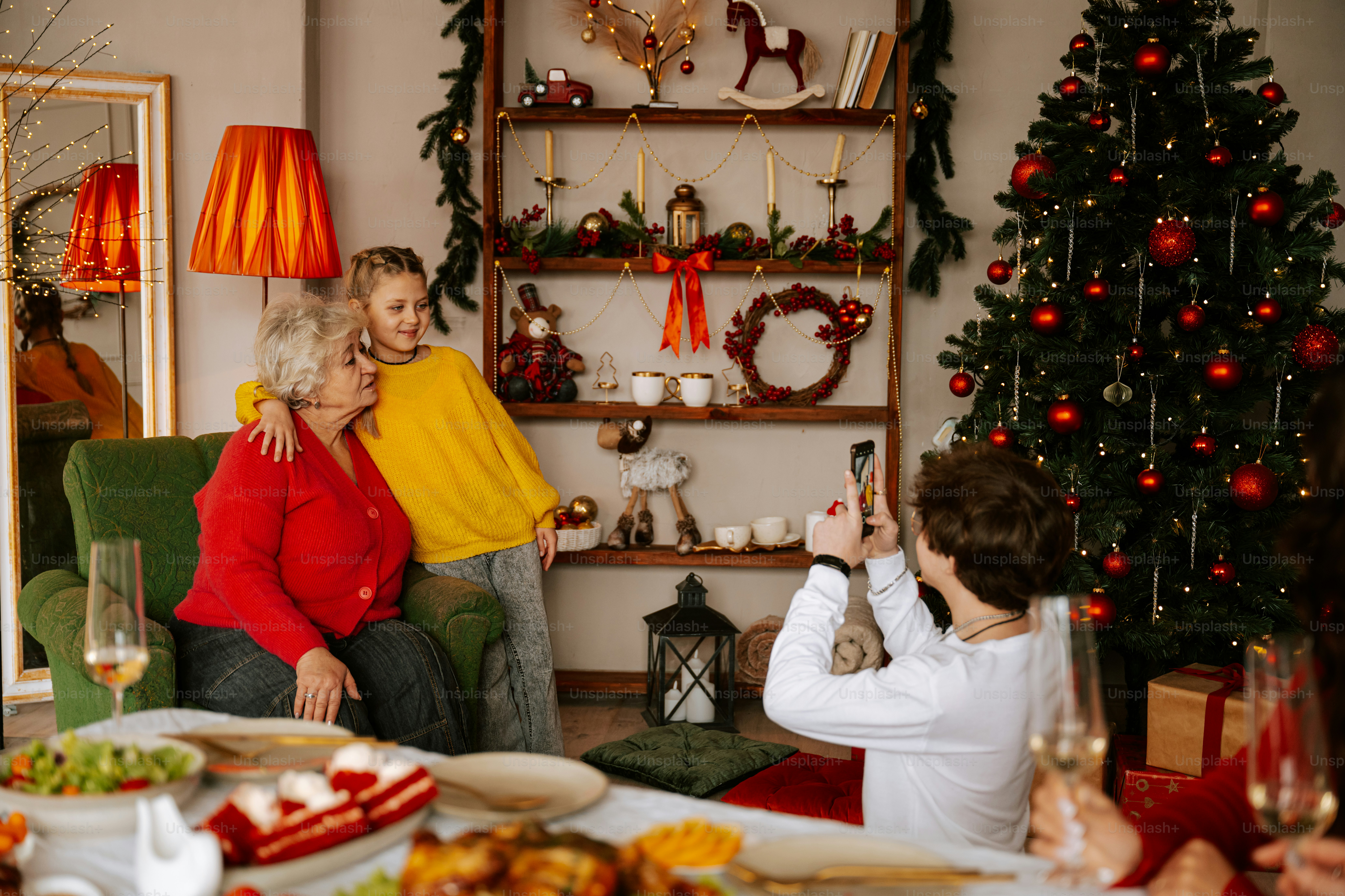 A man and woman sitting on a couch in front of a christmas tree