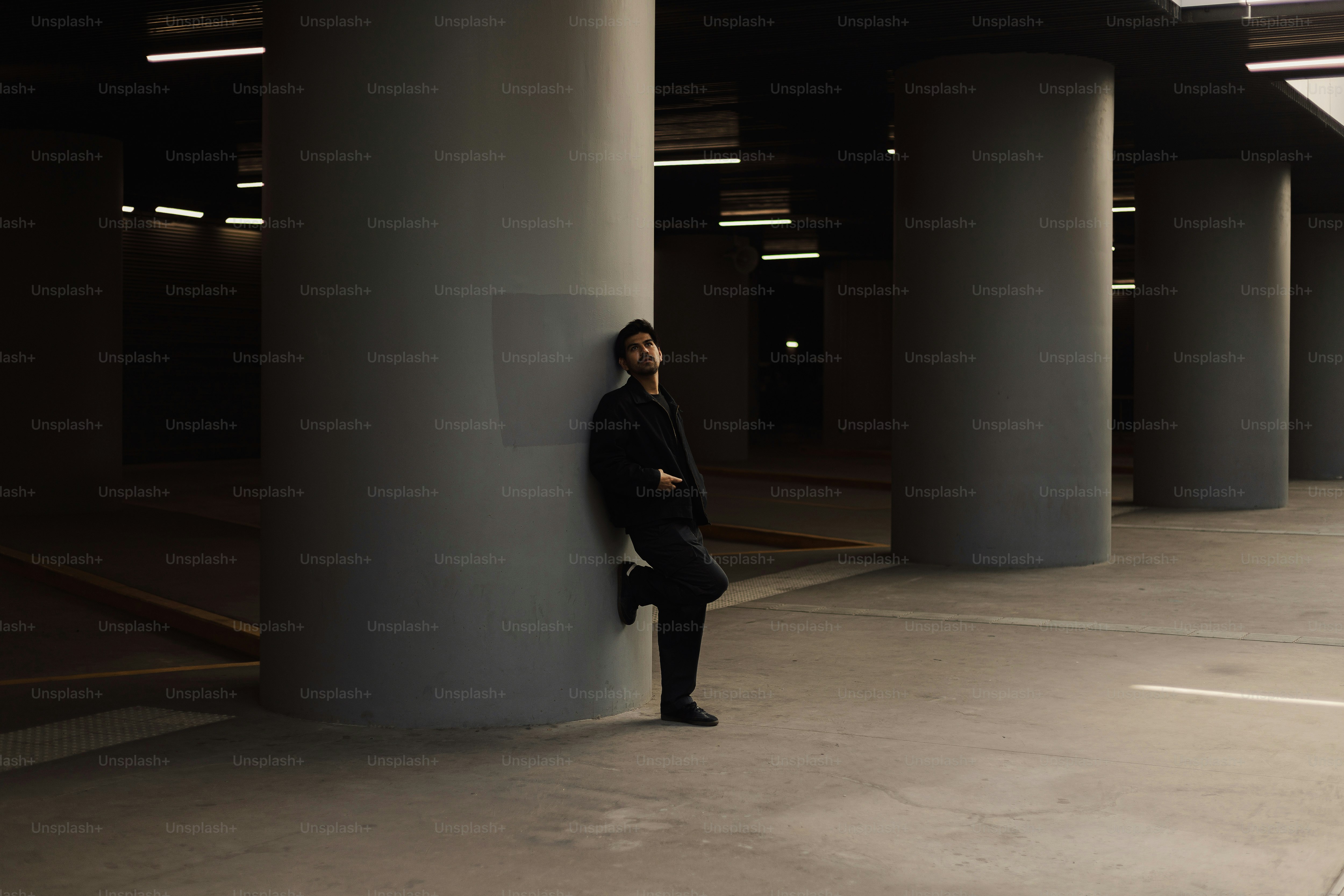A man leaning against a pillar in a parking garage
