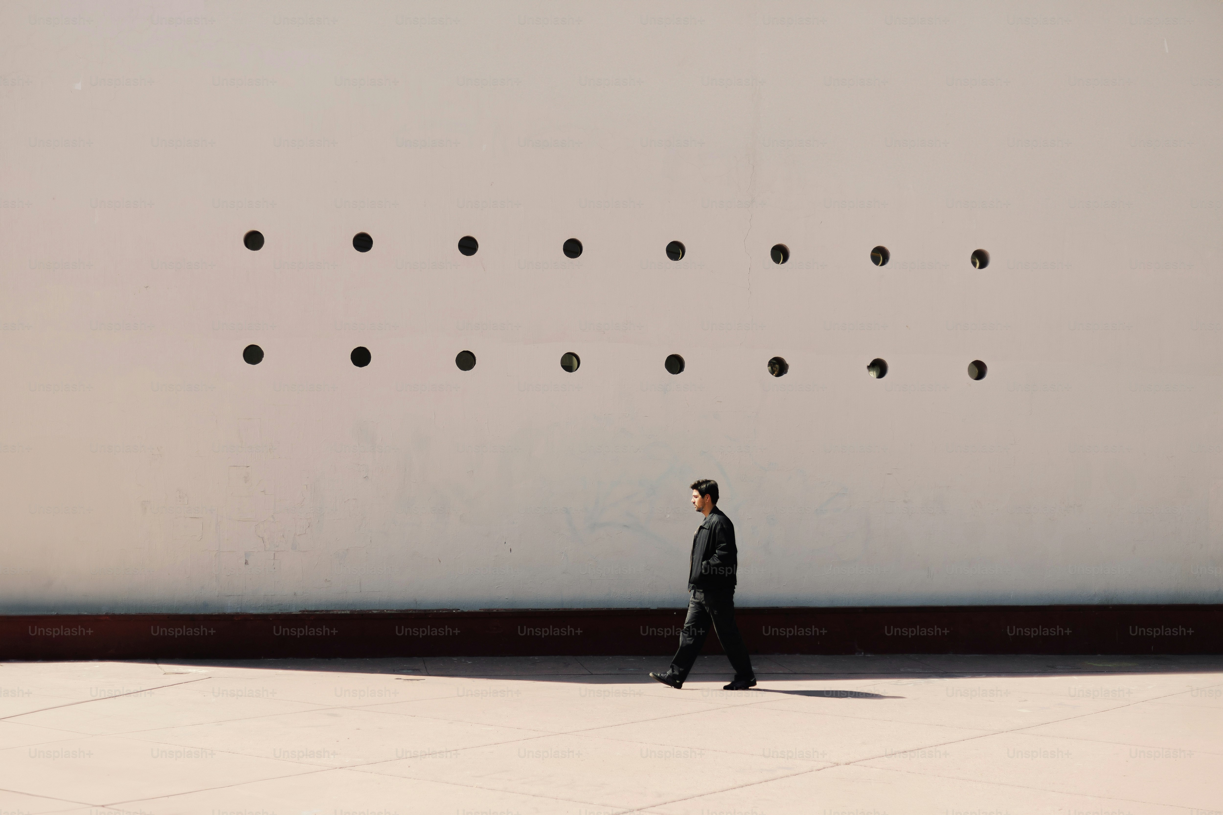A man in a suit walking past a large wall