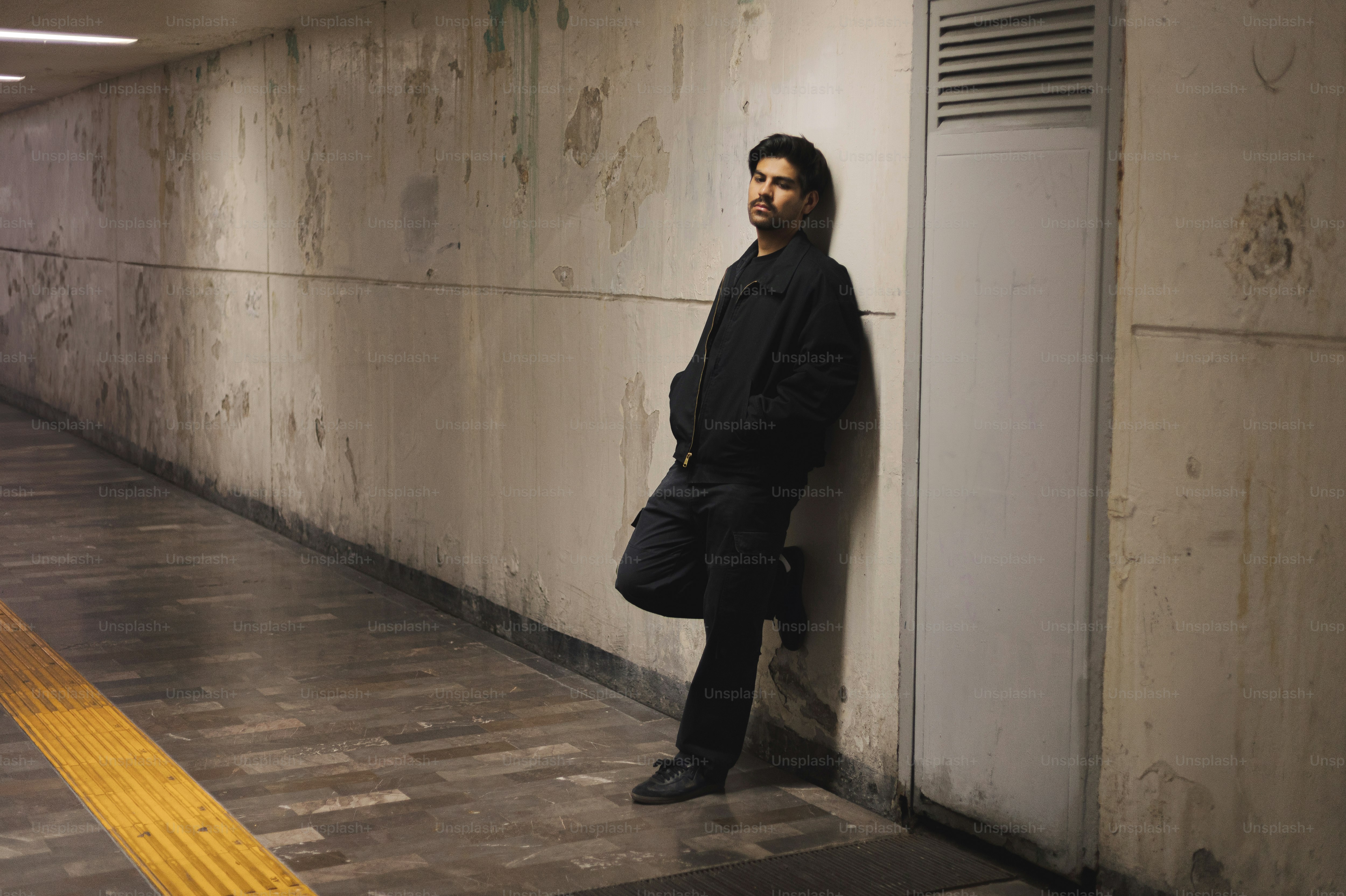 A man leaning against a wall in a tunnel