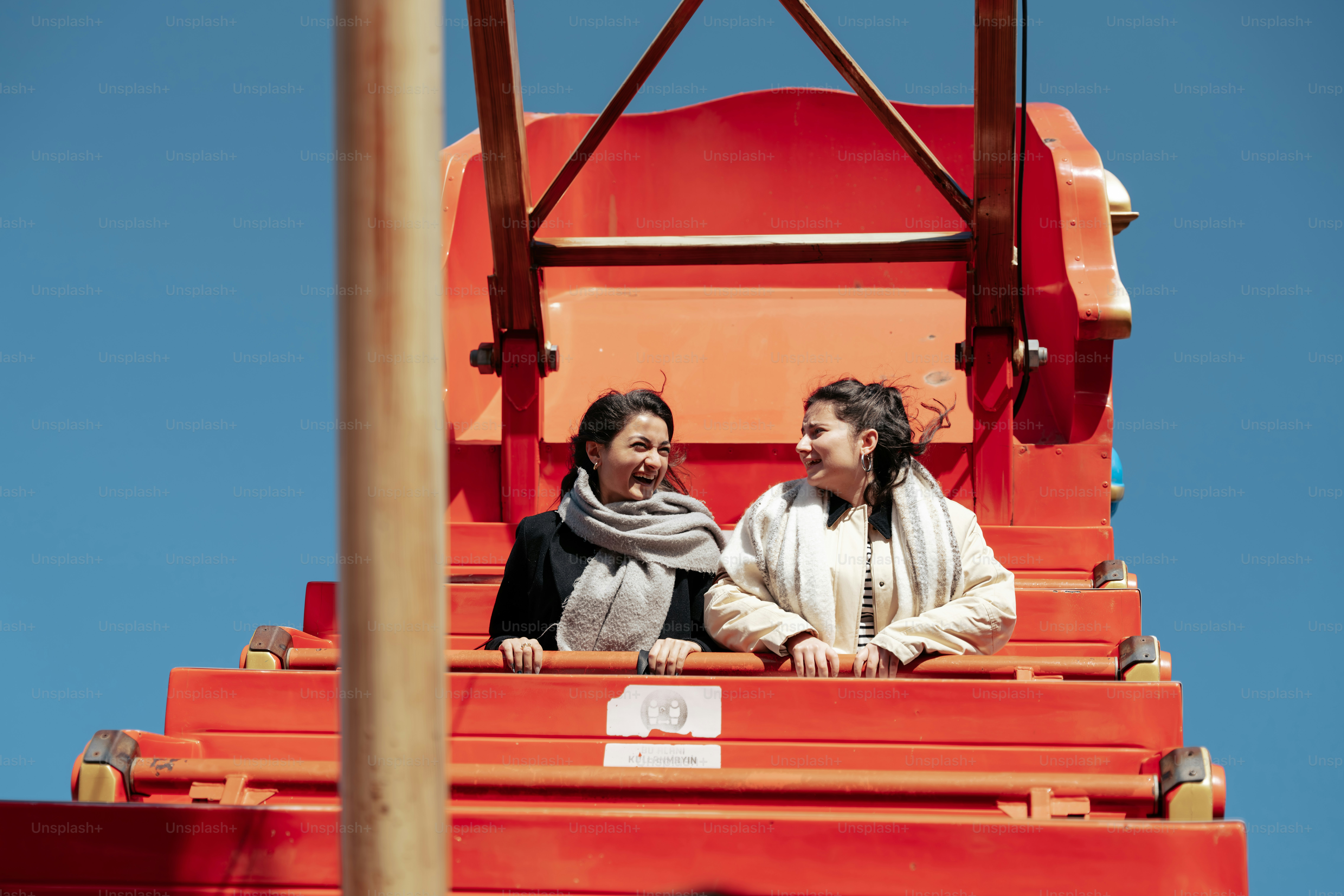 赤い構造物の上に座っている女性カップル