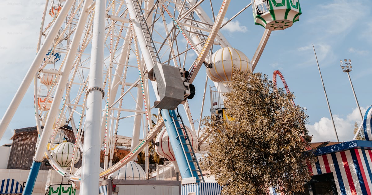 A large ferris wheel sitting next to a tall building photo – Fairground ...