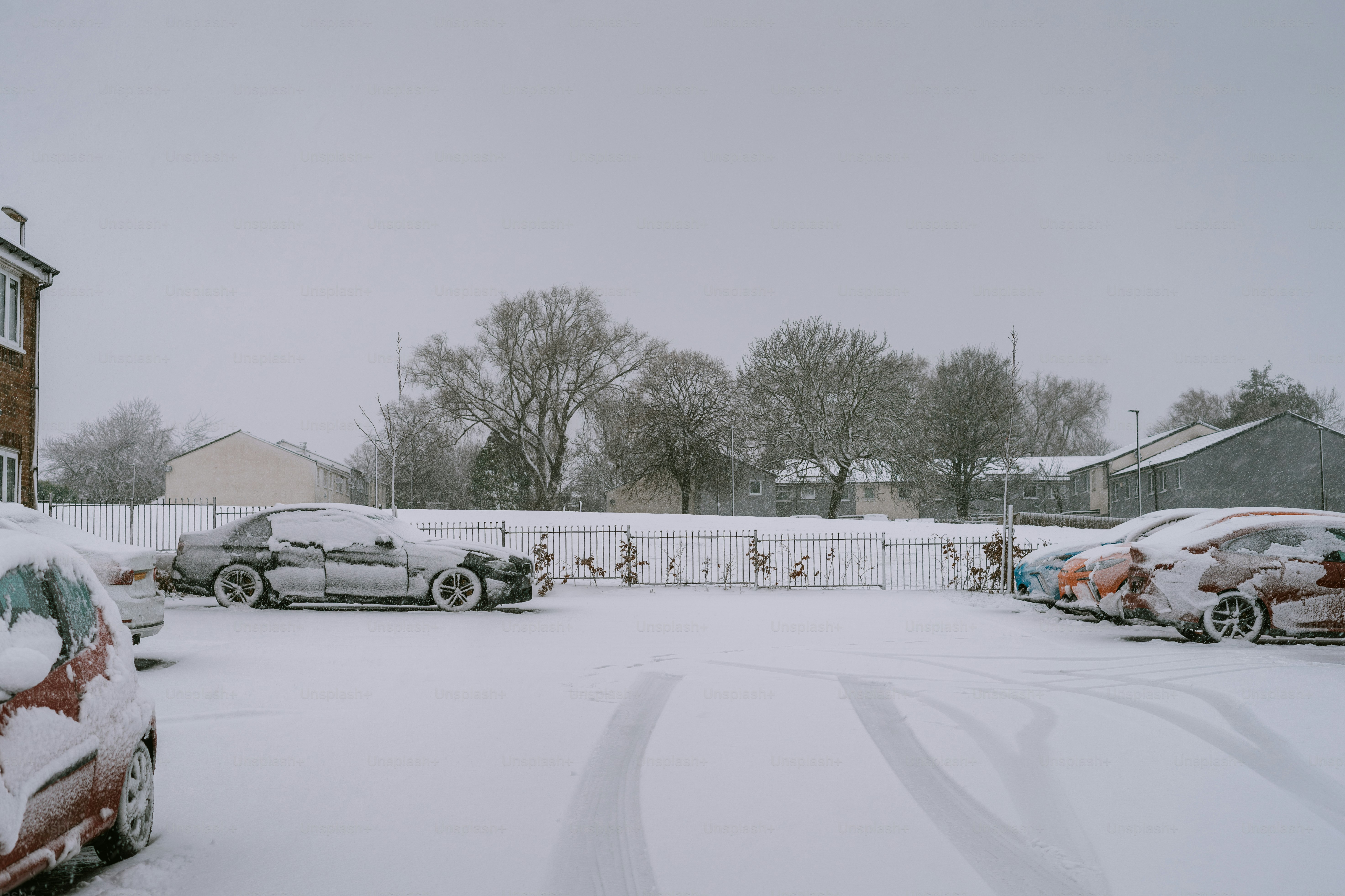 A snow covered street with cars parked on it