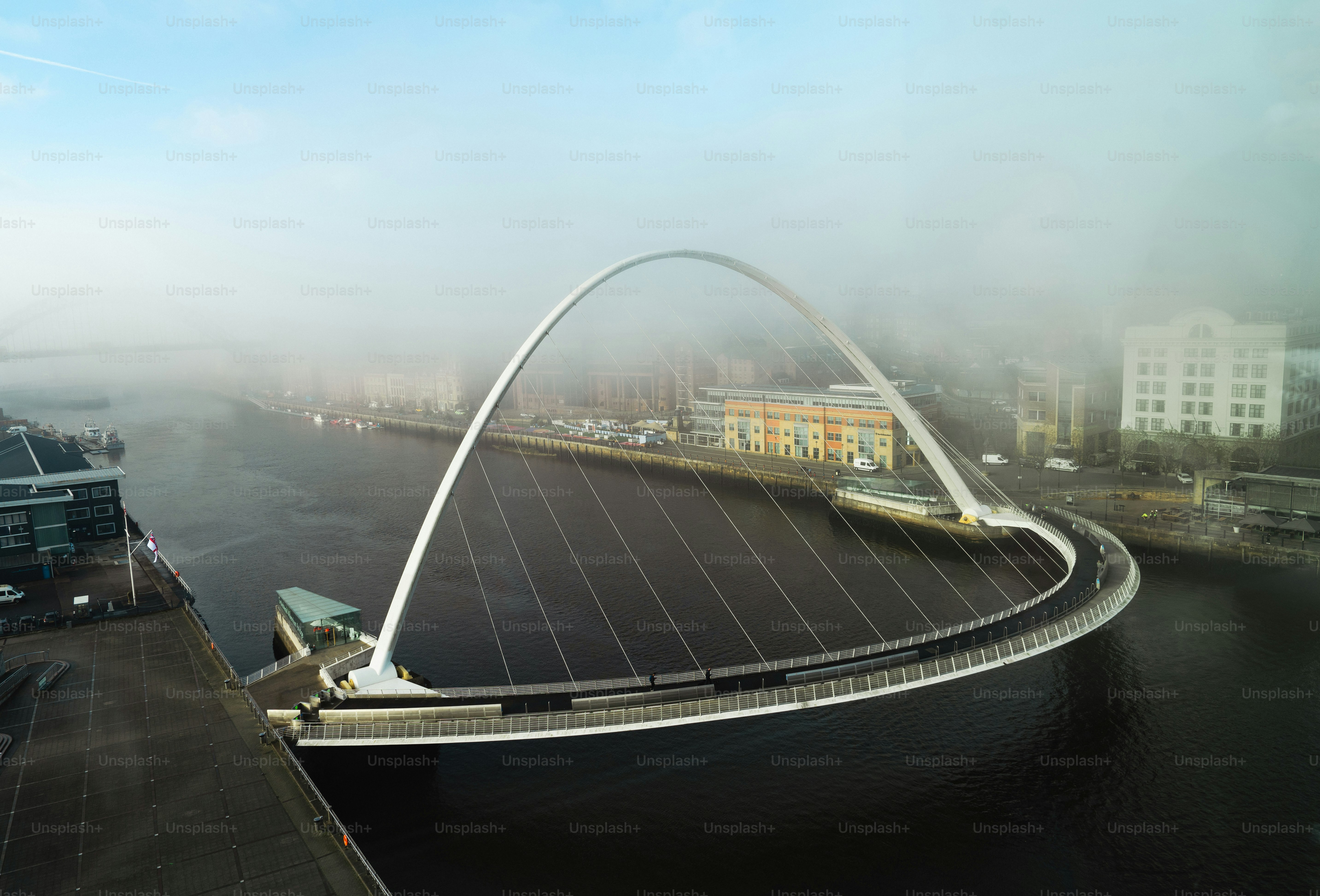 A foggy view of a bridge over a body of water