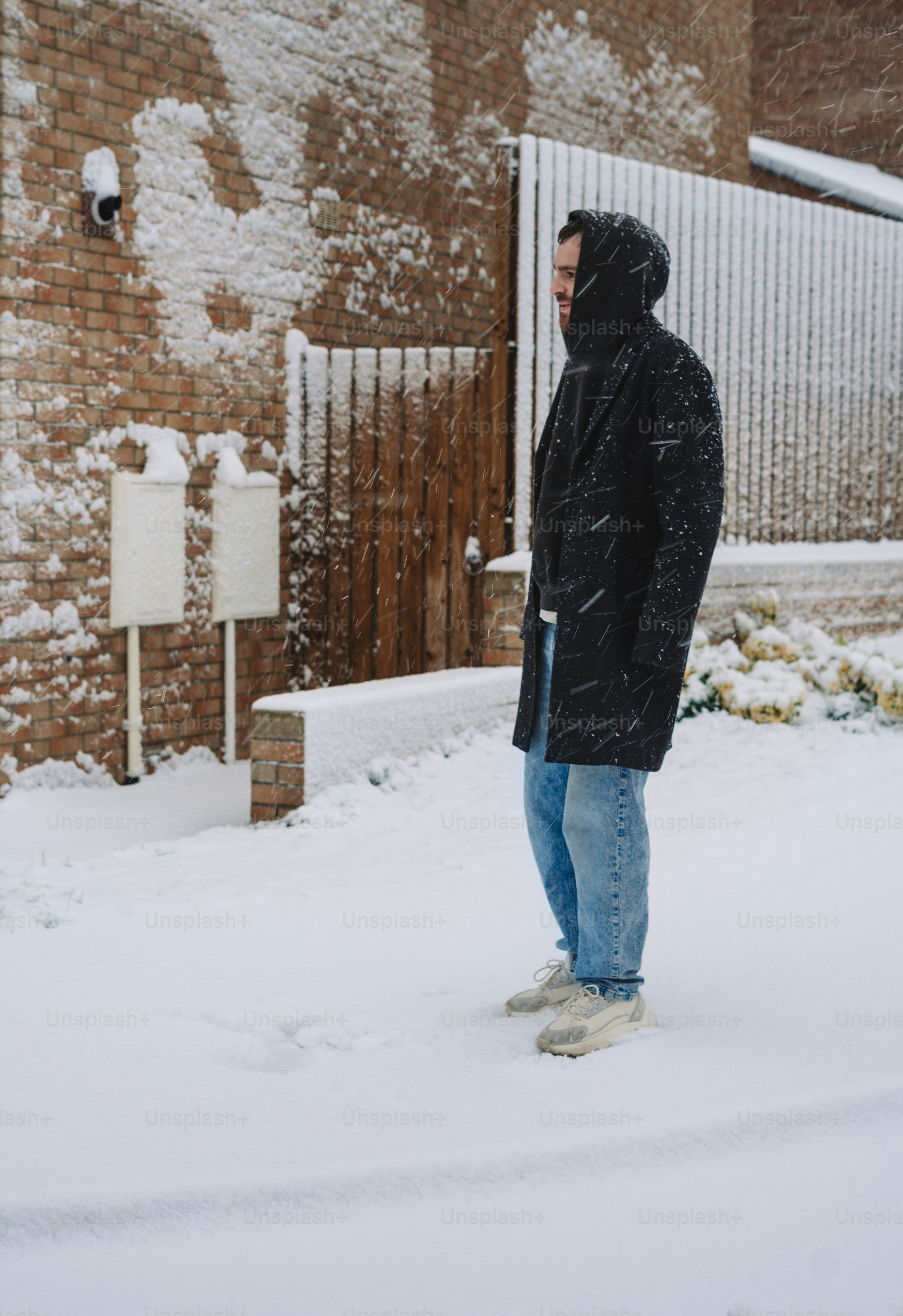 A man standing in the snow in front of a building