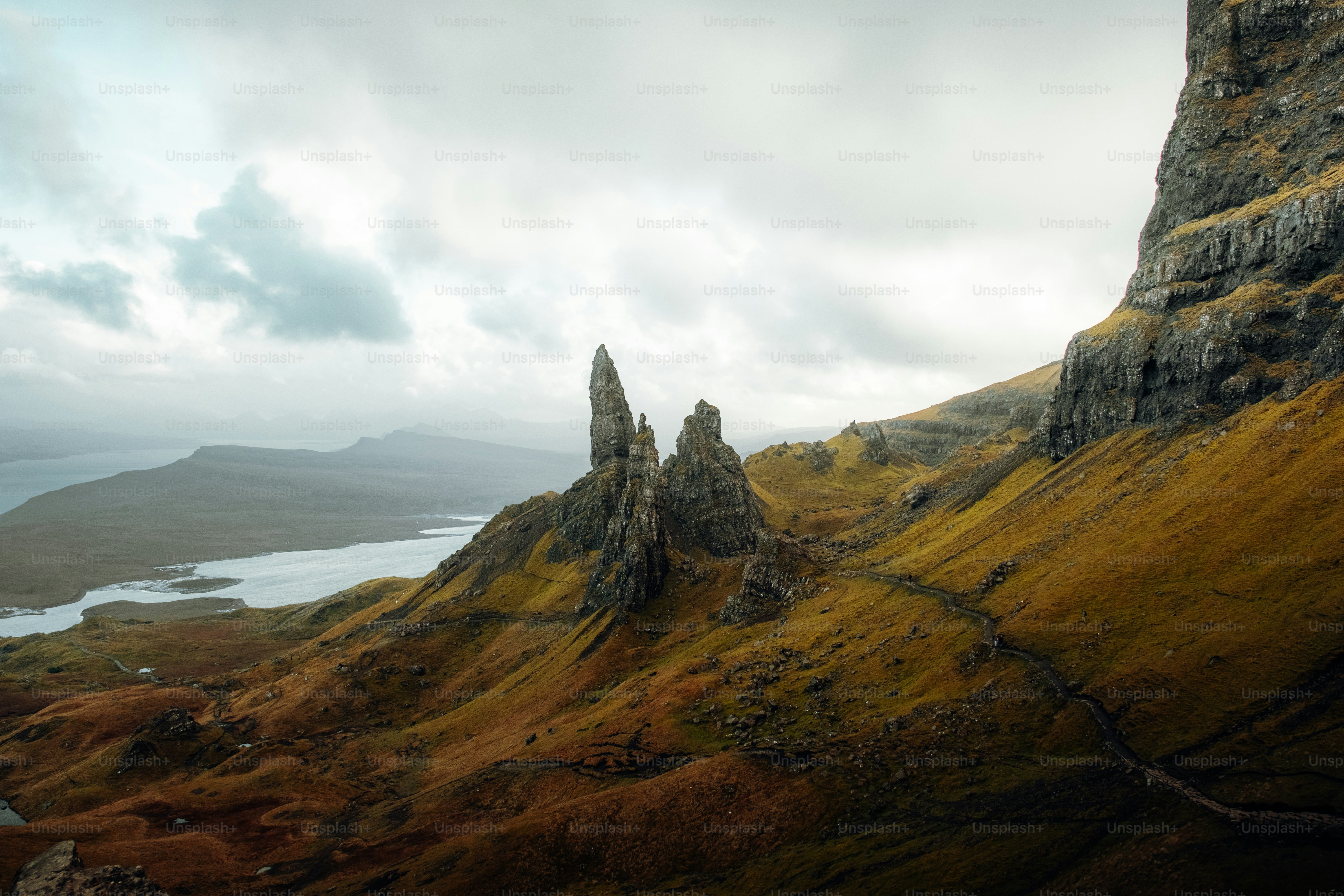 A rocky mountain with a body of water in the distance