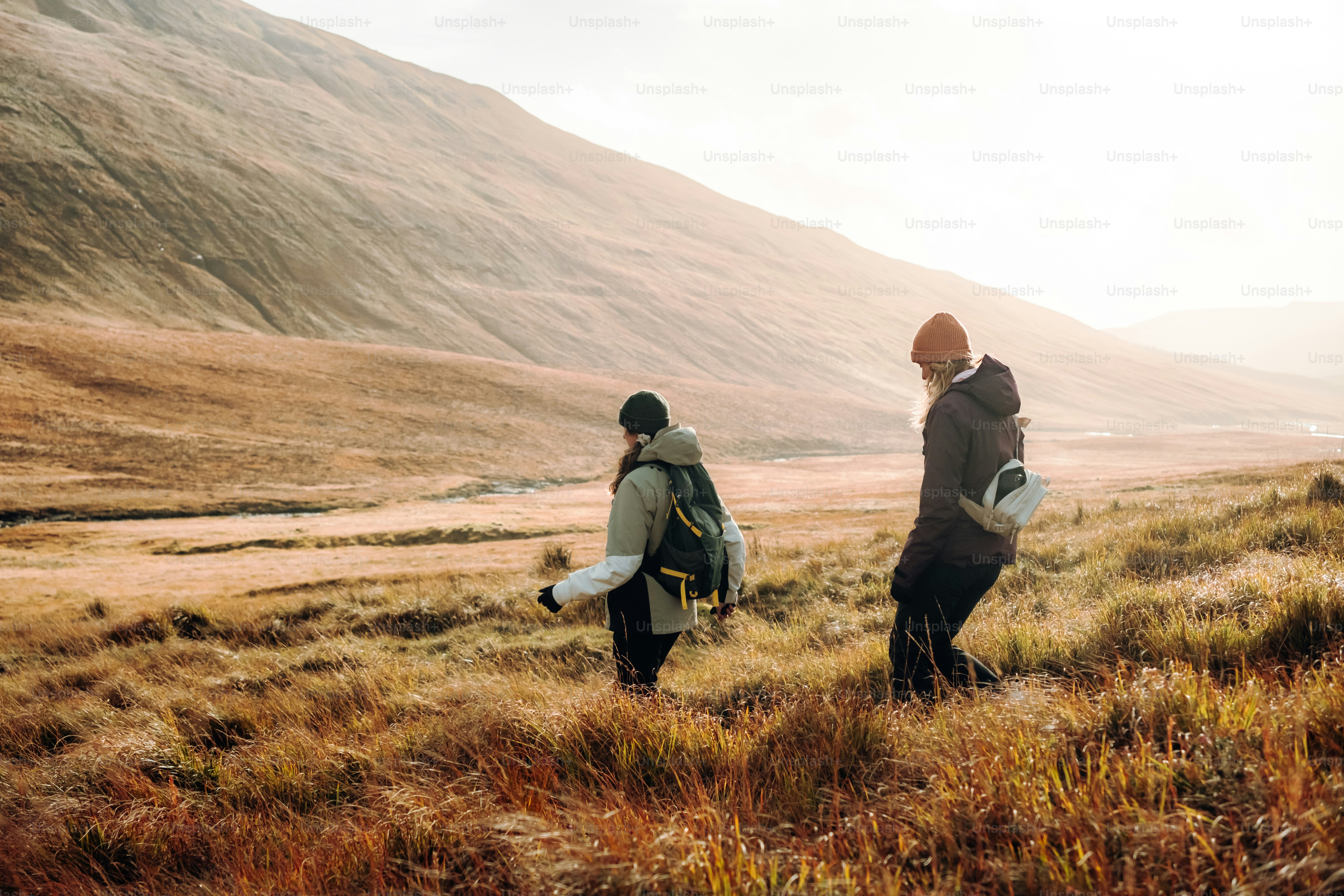 A couple of people walking across a grass covered field