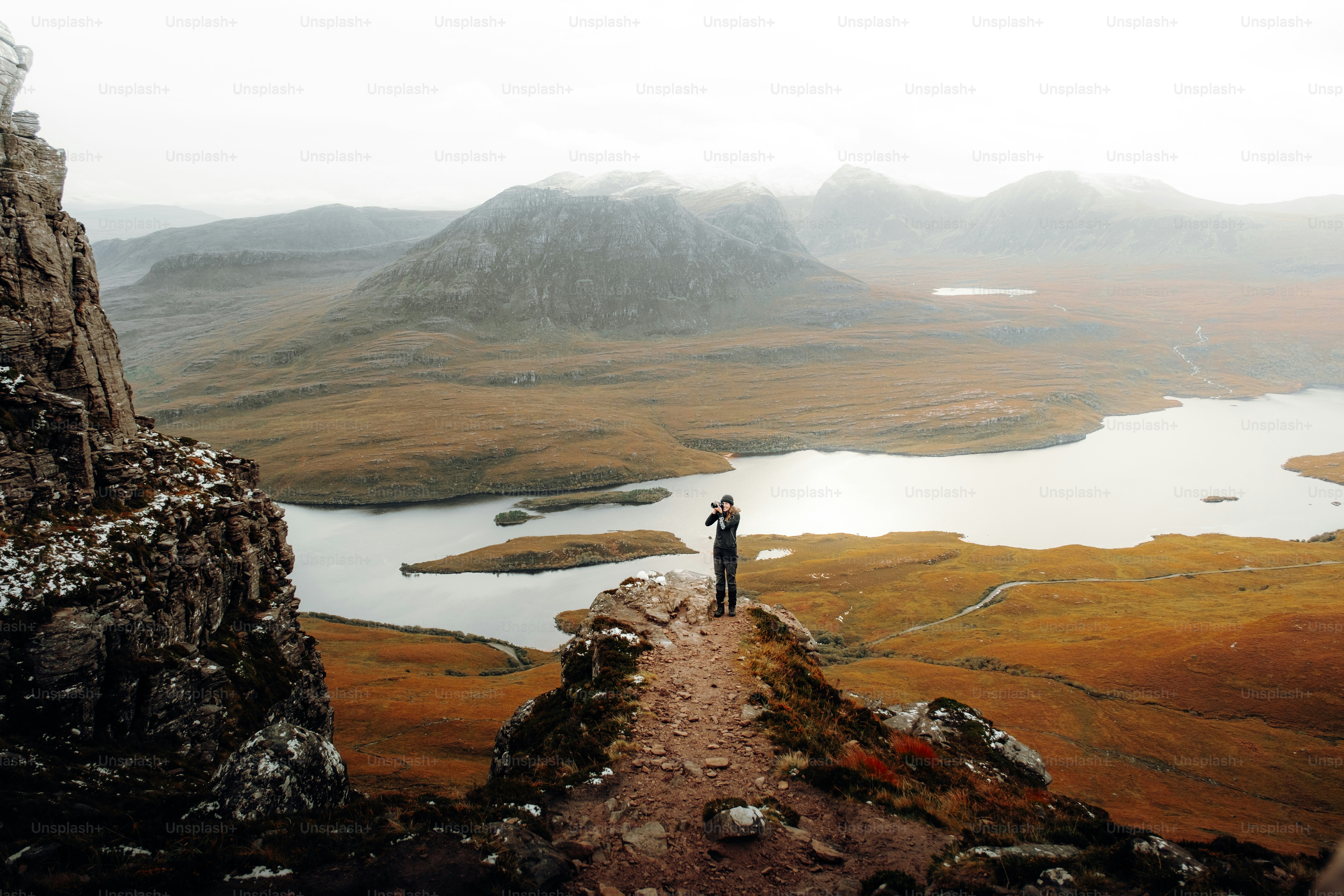 A person standing on top of a mountain overlooking a lake photo ...