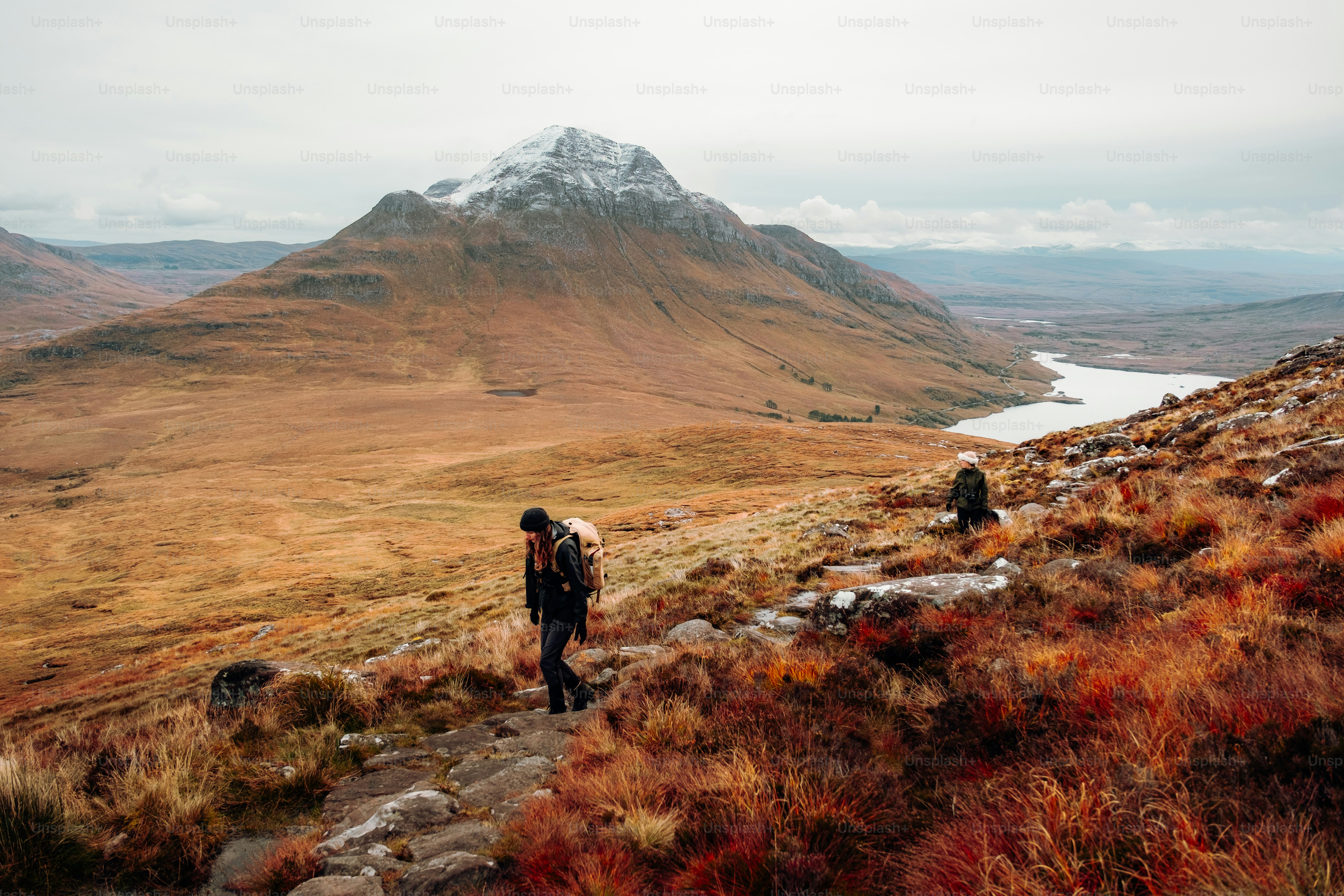 A person walking up a hill with a mountain in the background