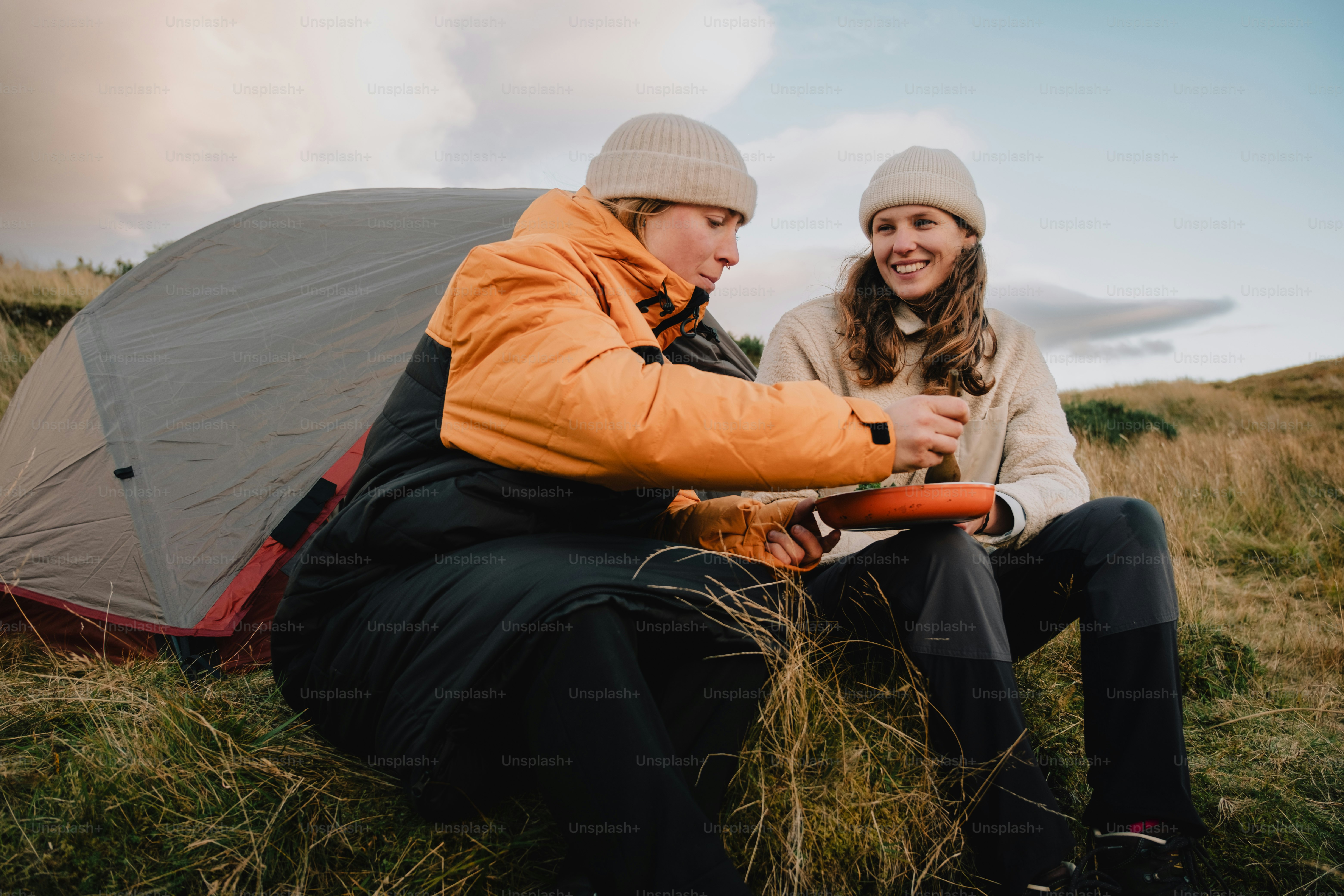 A couple of people sitting next to a tent