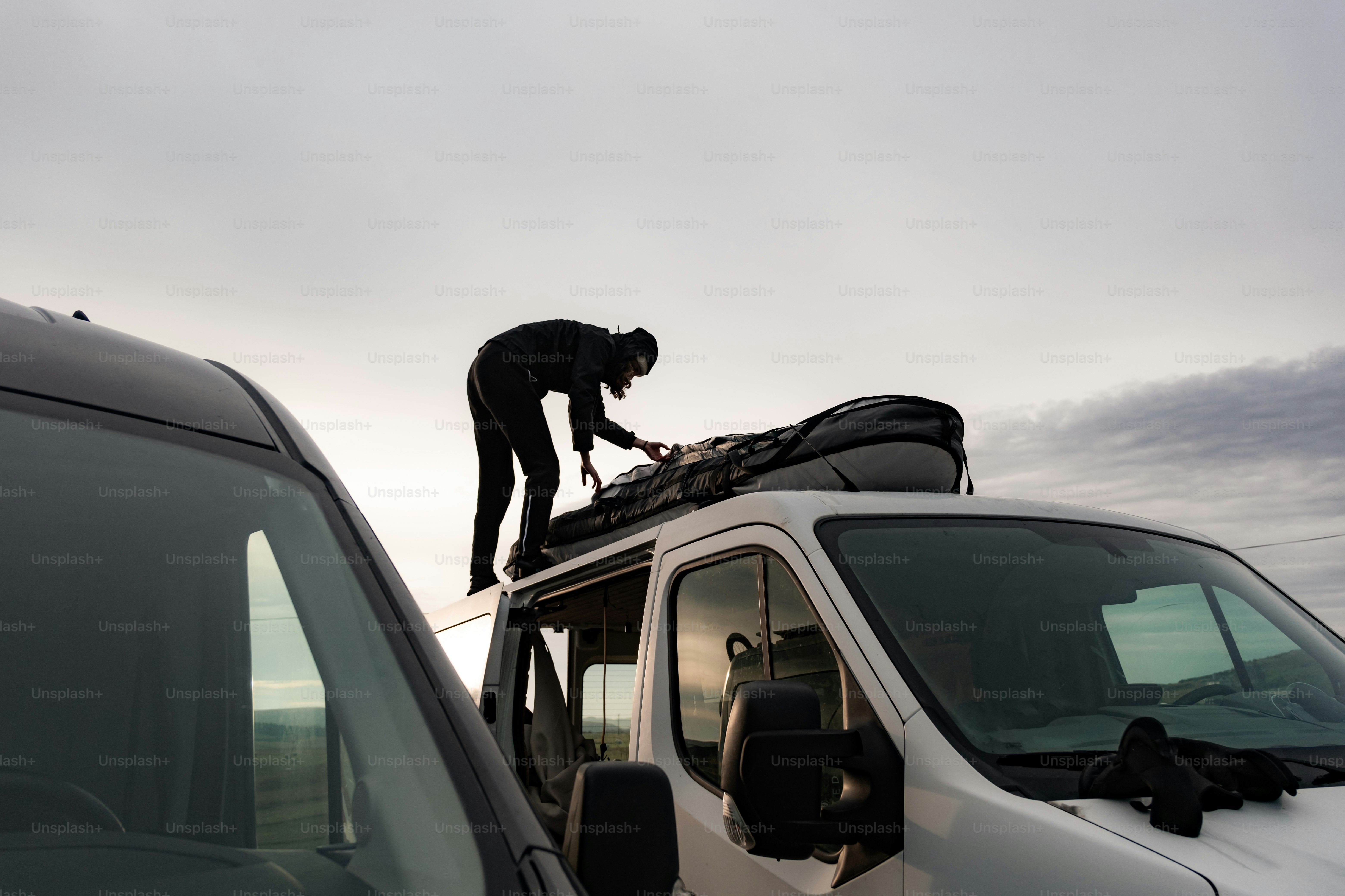 A man standing on top of a van next to a van