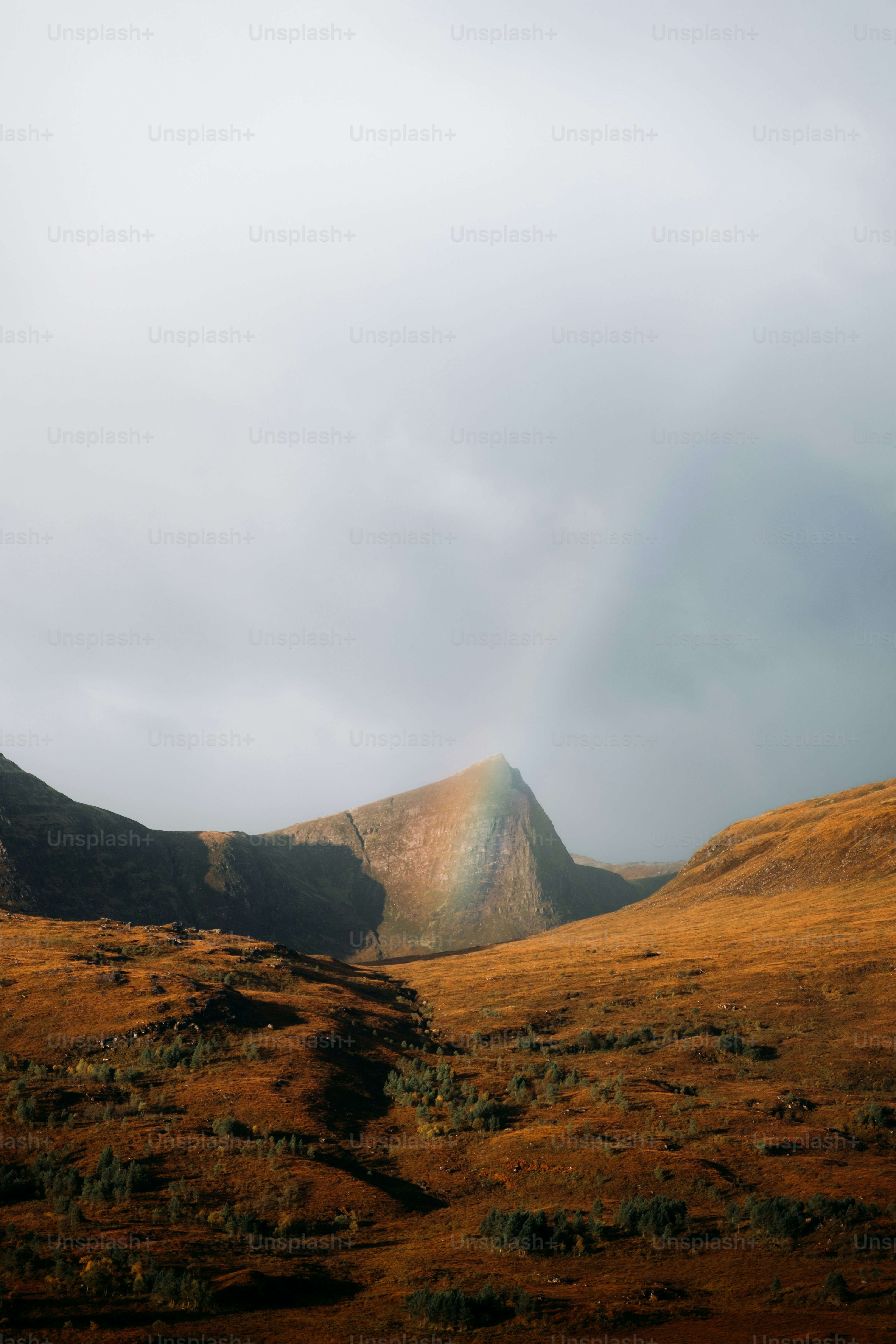 A rainbow shines in the sky over a mountain