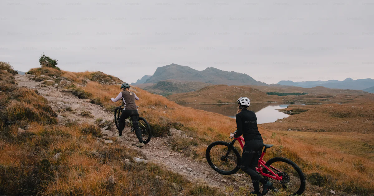 A couple of people riding bikes down a hill photo – Travel Image on ...