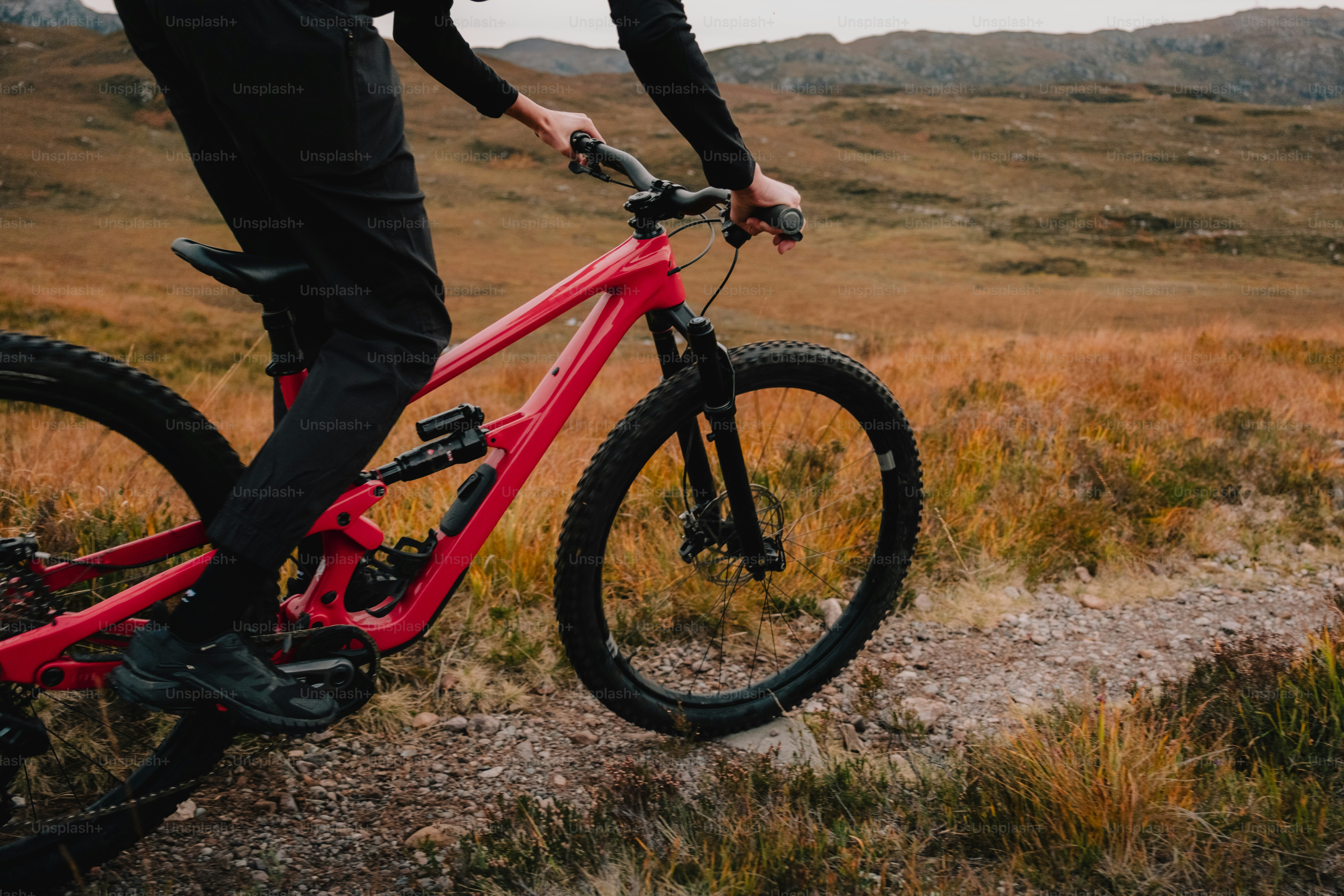 Un uomo in giacca e cravatta in sella a una mountain bike rossa