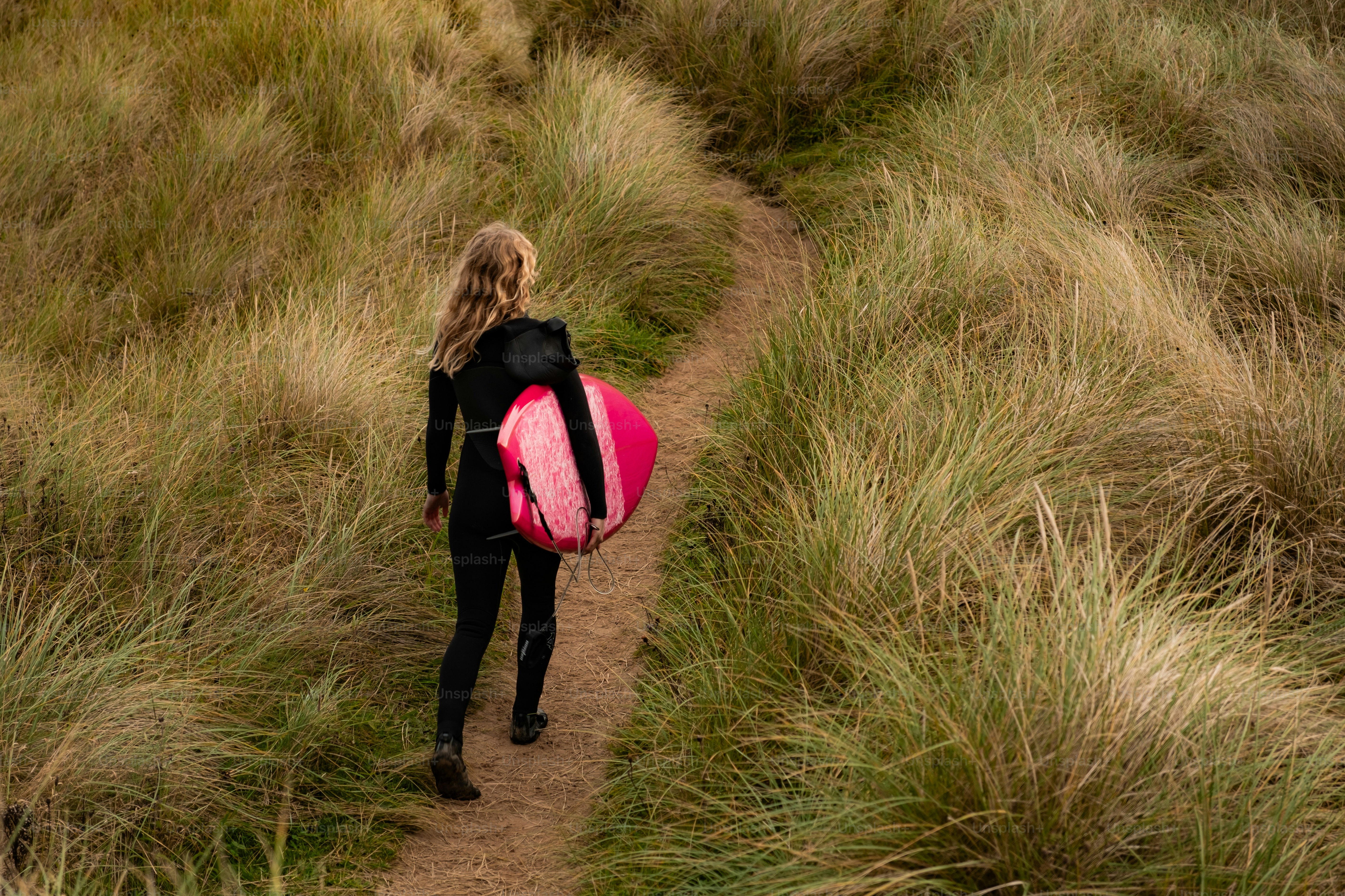 A woman with a pink backpack walking up a trail