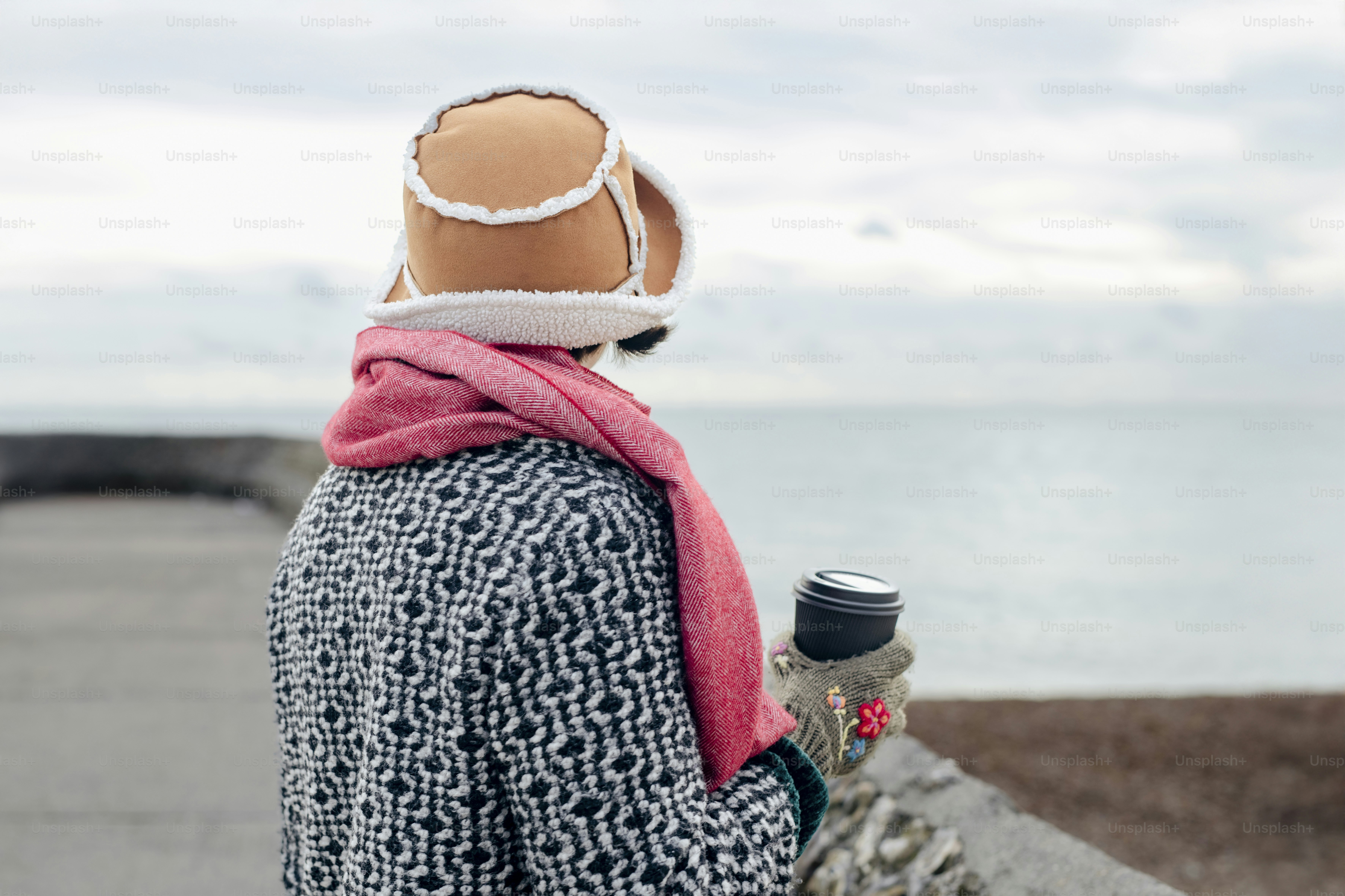 Una persona con sombrero y bufanda de pie junto a una bicicleta