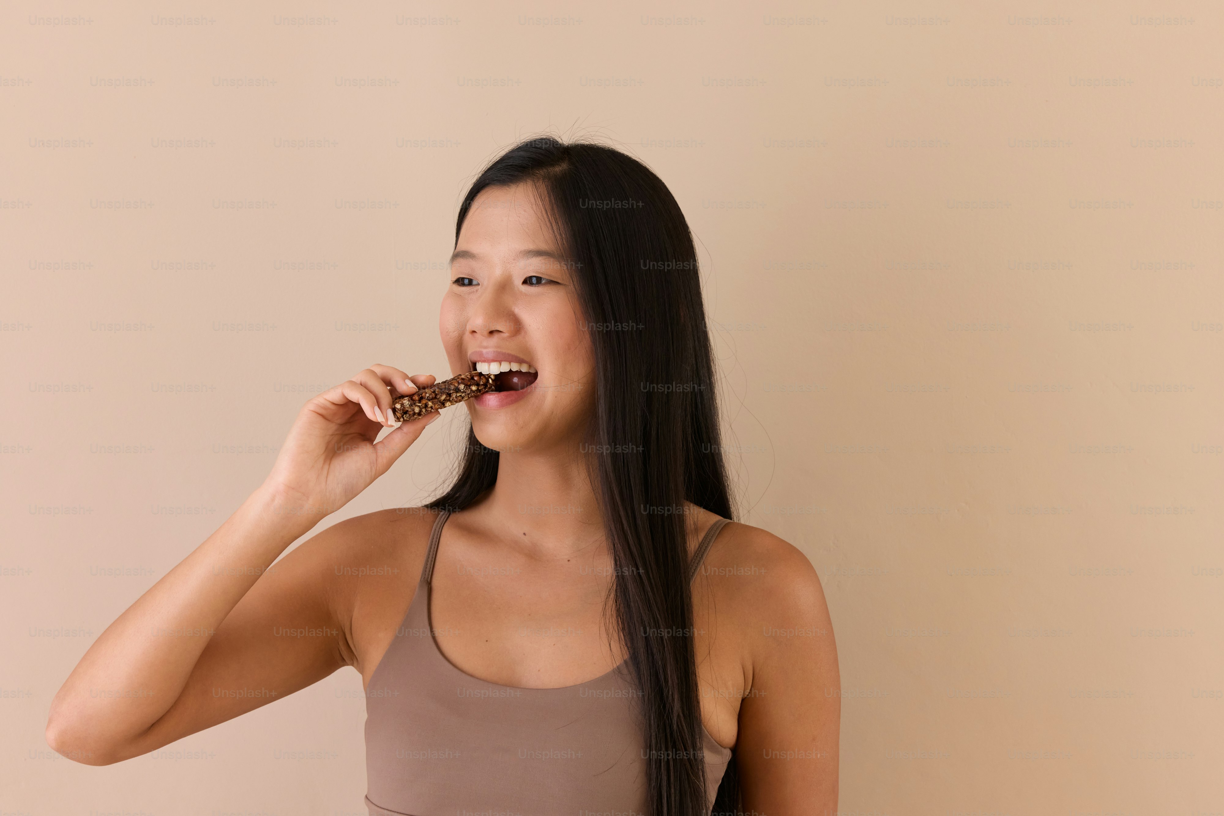 A woman brushing her teeth while wearing a tank top