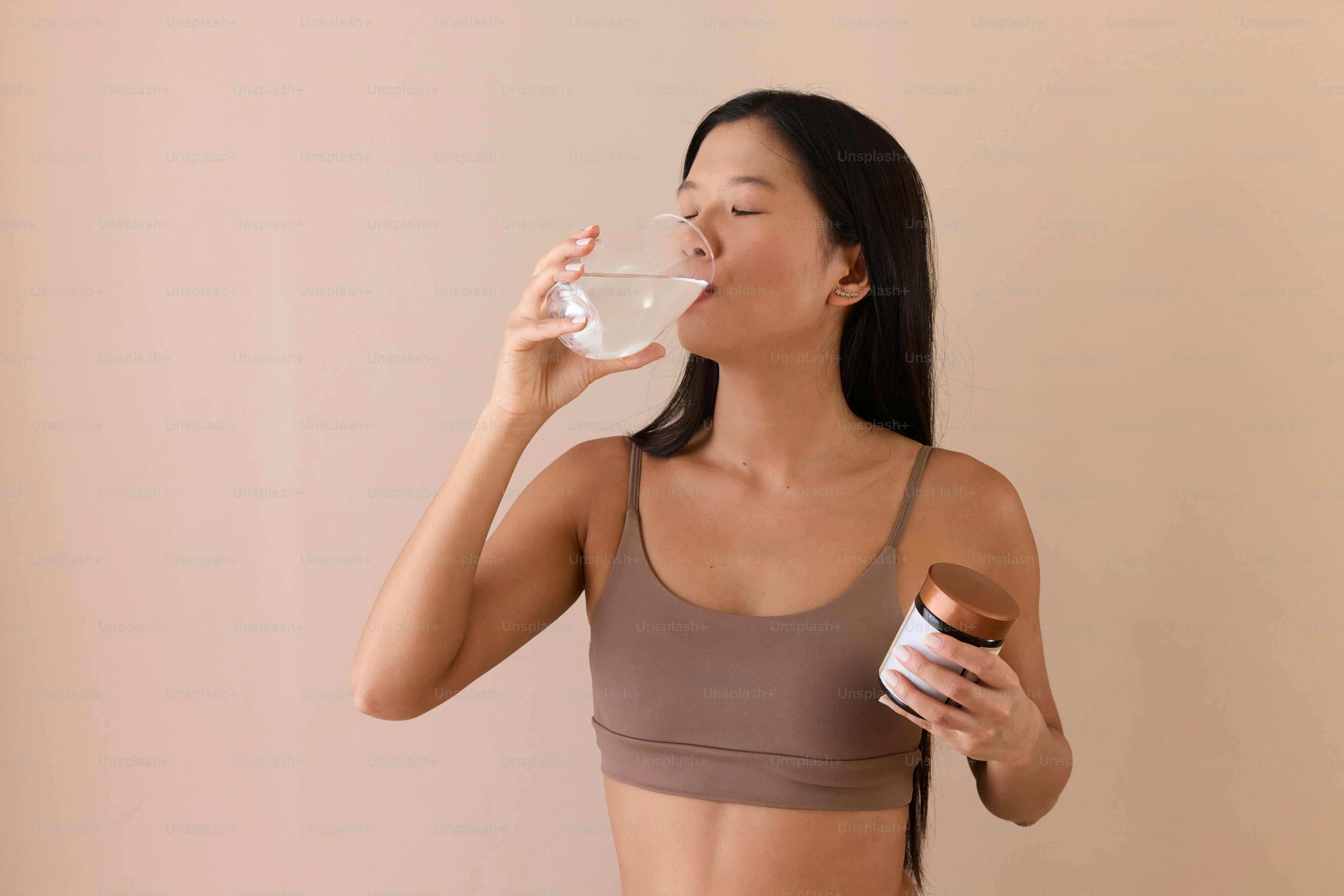 Una mujer bebiendo un vaso de agua y sosteniendo una rosquilla