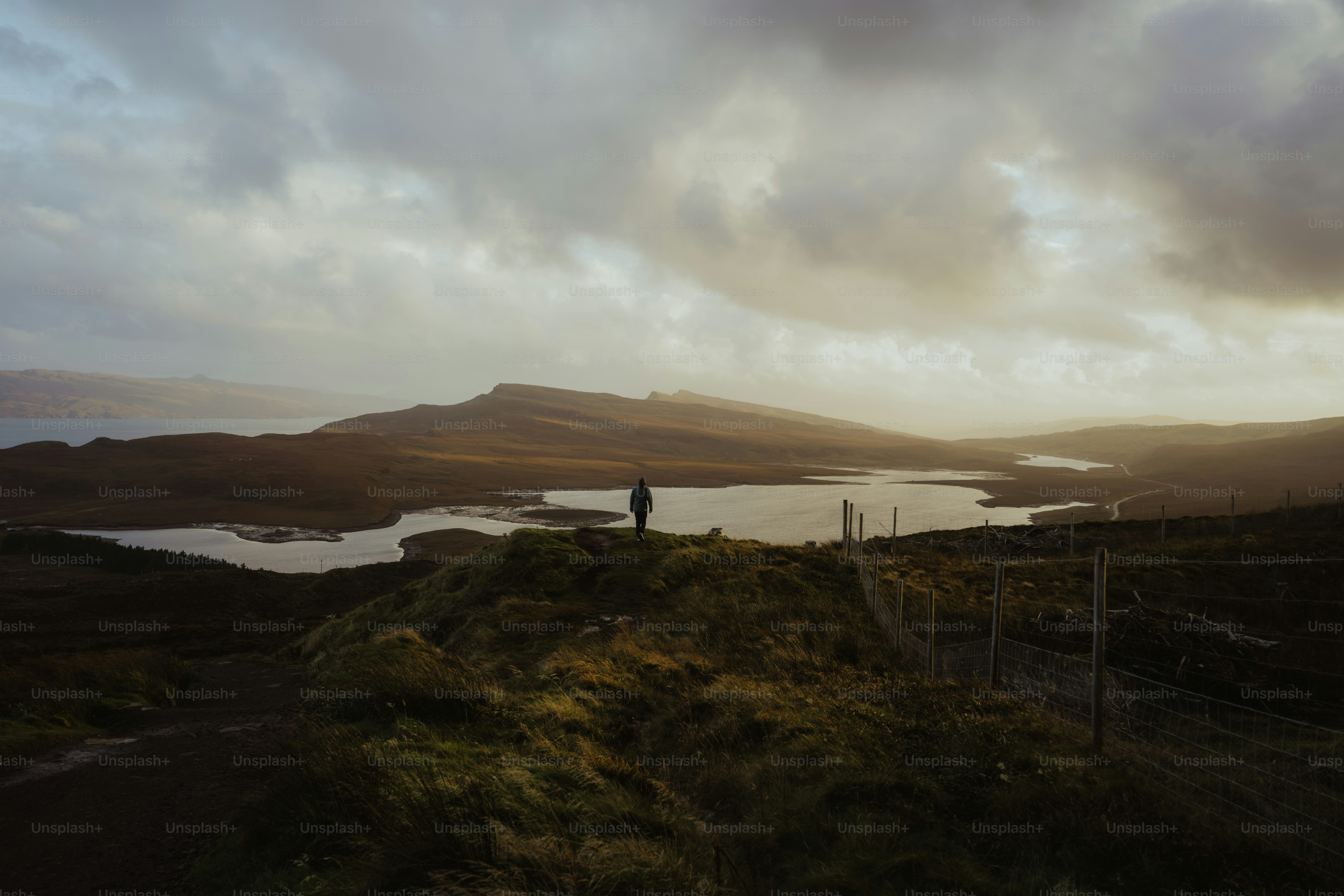 A person standing on a hill overlooking a body of water