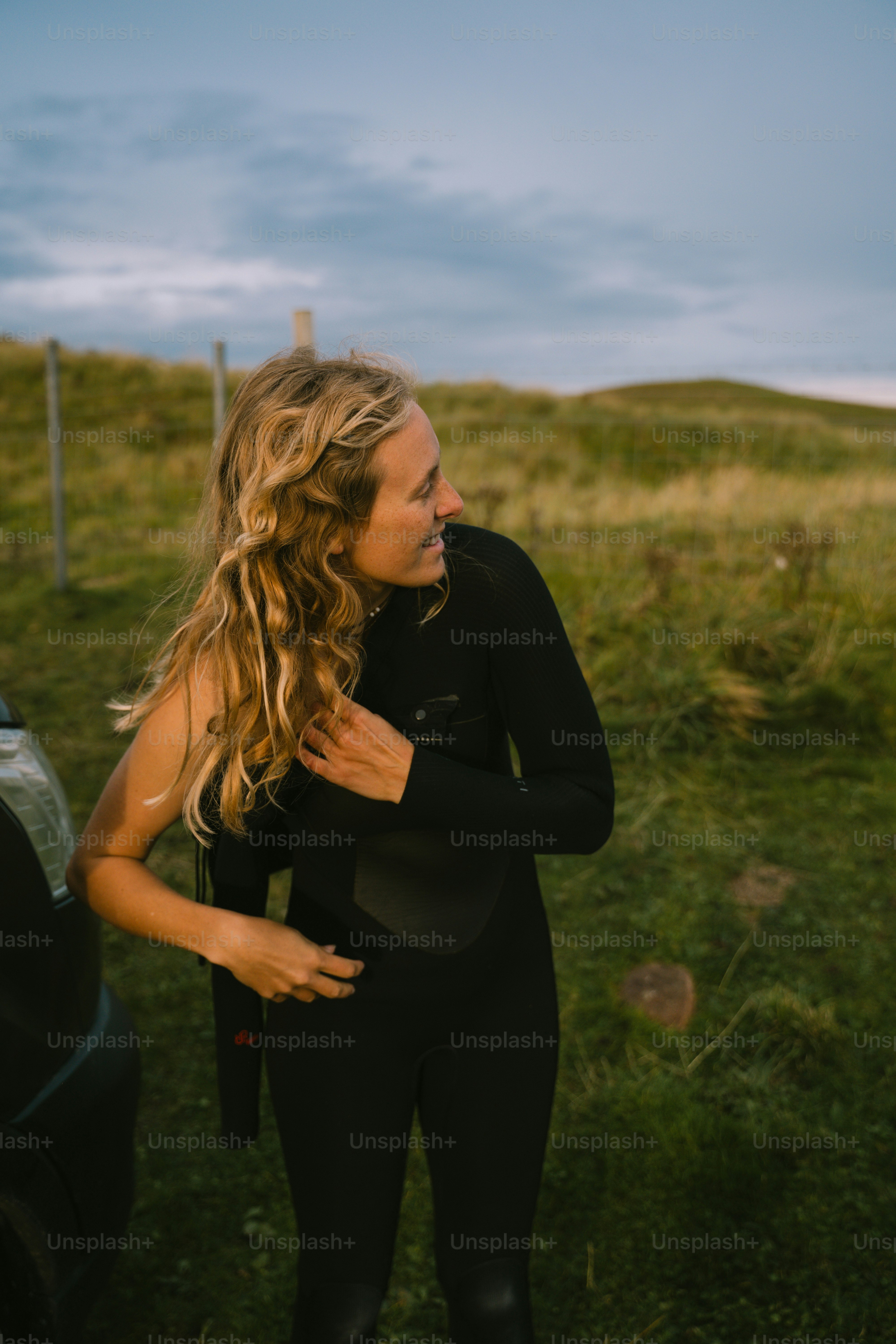 잠수복을 입은 여성이 차 옆에 서 있다